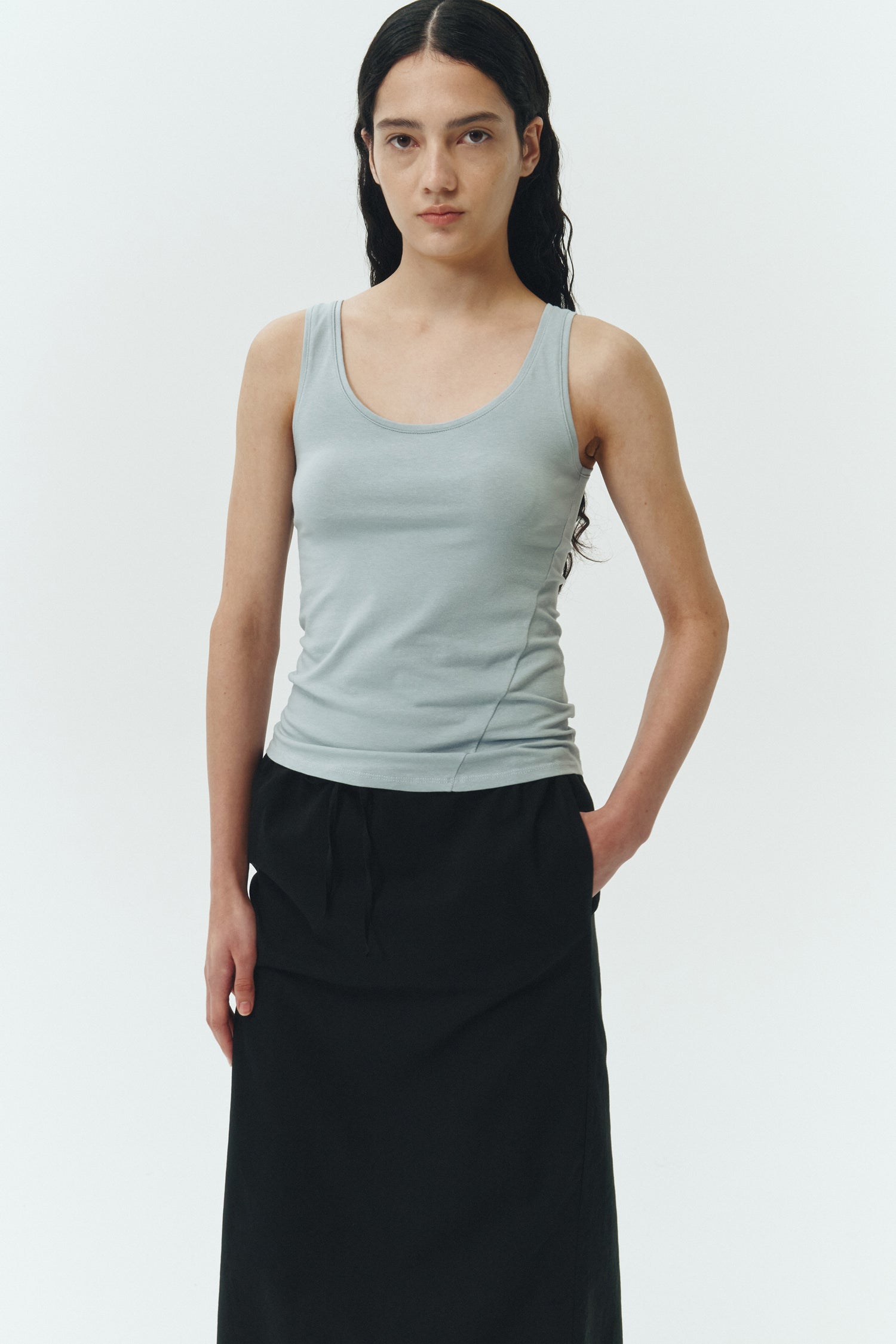 Amelia Skirt in black, a lightweight cotton midi skirt with inner drawstring waist, hidden side pockets, lined layers, raw-edge hem, and a center back slit for ease and movement