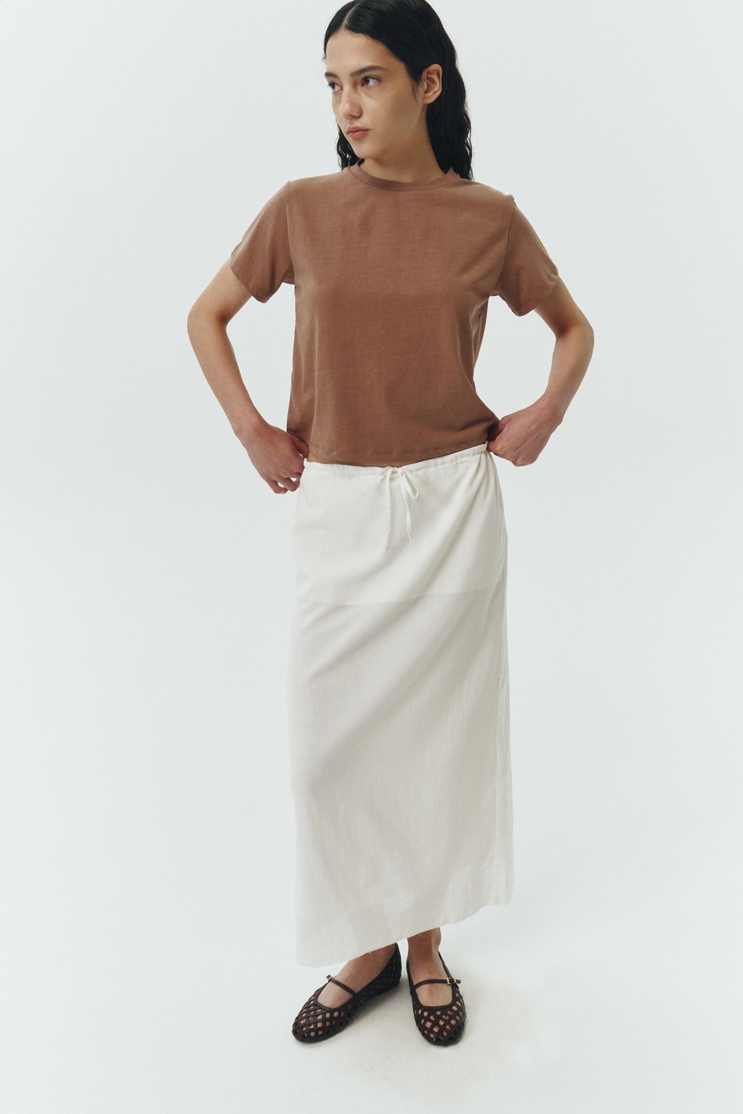 Amelia Skirt in white, a lightweight cotton midi skirt with inner drawstring waist, hidden side pockets, lined layers, raw-edge hem, and a center back slit for ease and movement