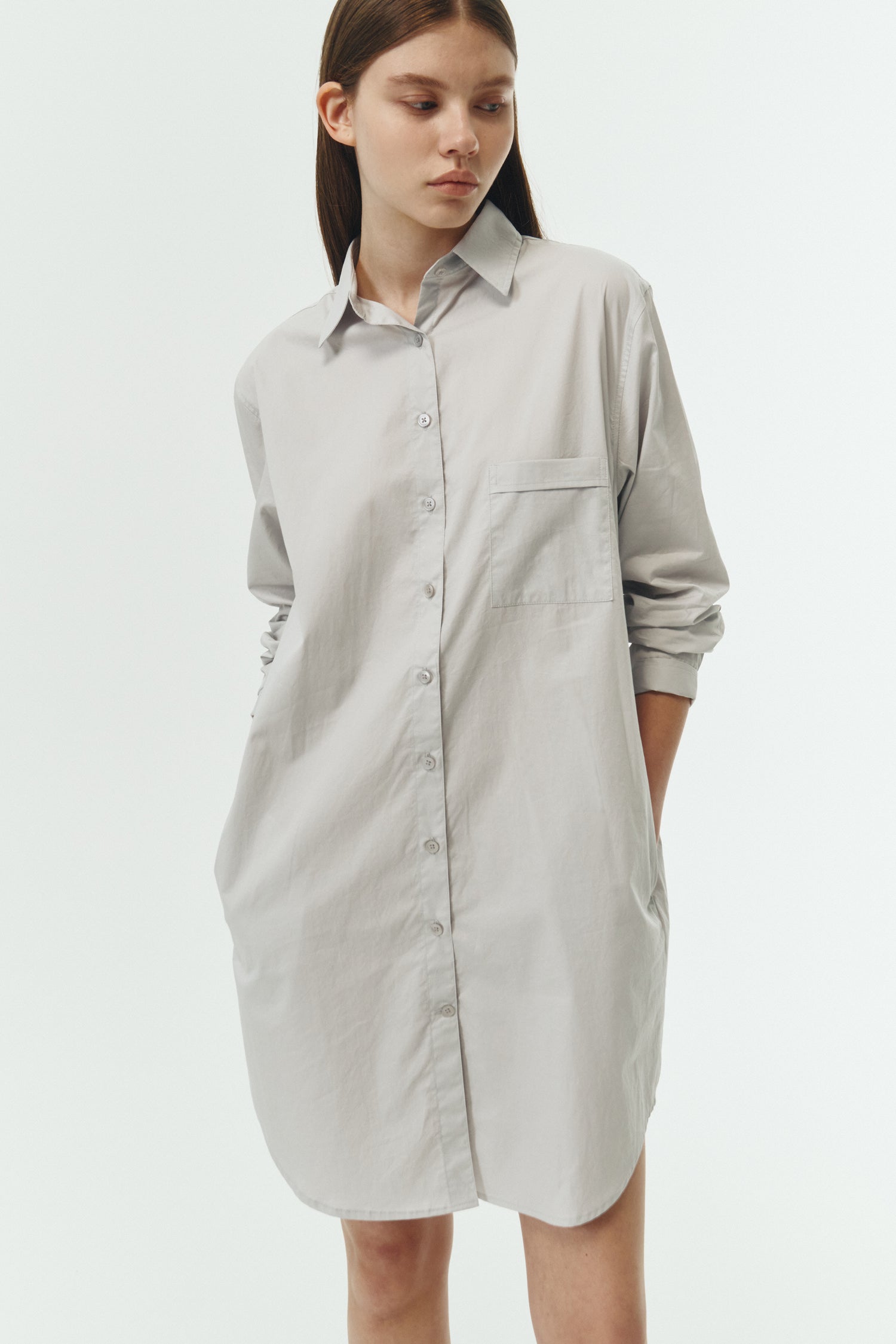 Cara Dress in cloud gray, long sleeve cotton shirt dress with front chest pocket, curved hem, hidden side pockets, and a relaxed silhouette.