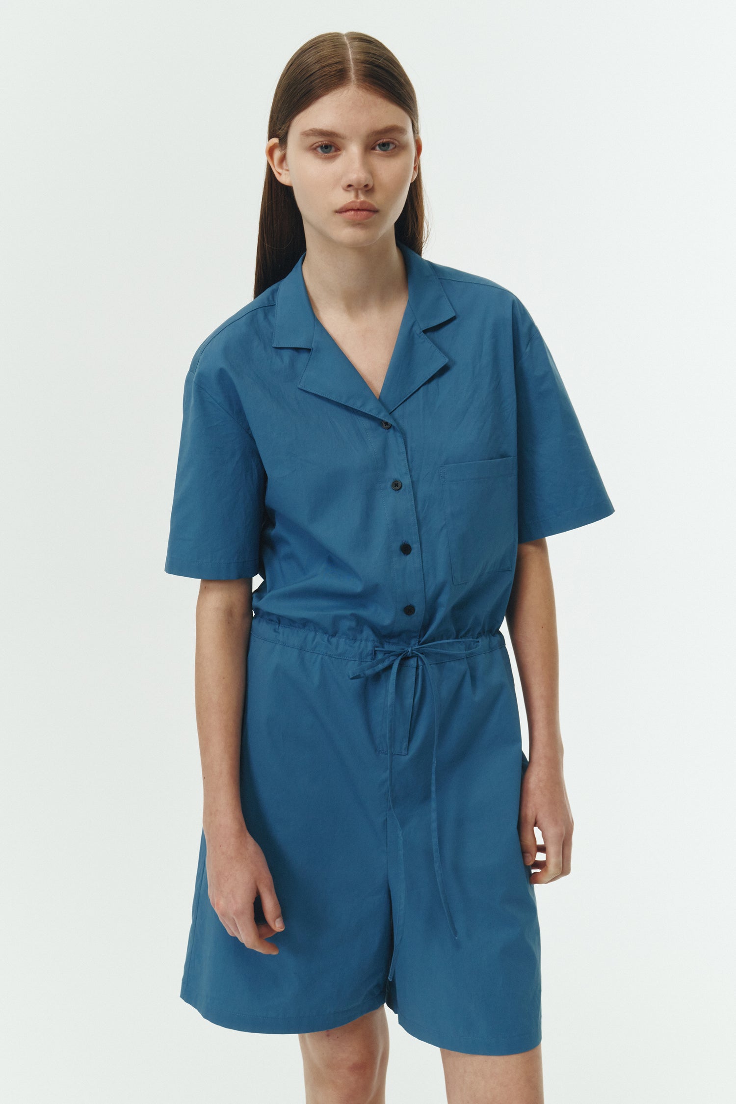 Emma Jumpsuit in blue green, short-sleeve cotton jumpsuit with camp collar, front buttons, drawstring waist, and multiple pockets.