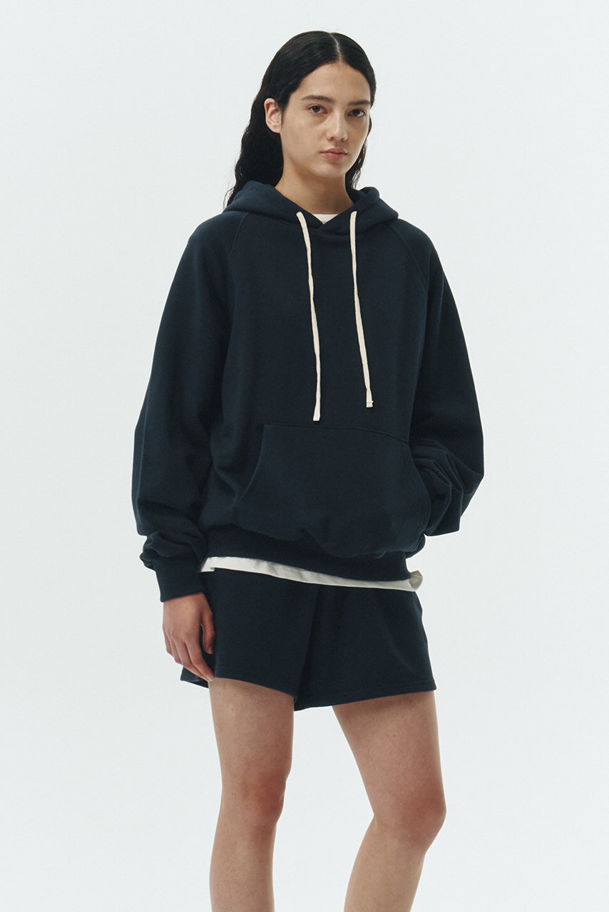 Kaia Hoodie in navy, oversized cotton French terry pullover with drawstring hood, raglan sleeves, kangaroo pocket, and ribbed trims.