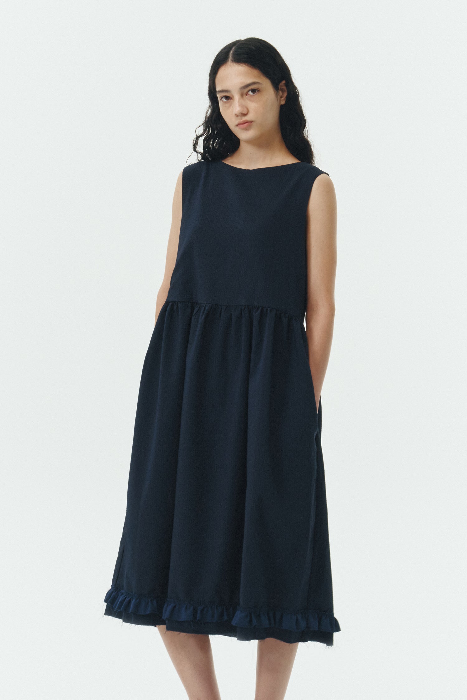 Pina Dress in navy, sleeveless cotton midi dress with shirring at waist and hem, hidden side pockets, and an open back with button closure.