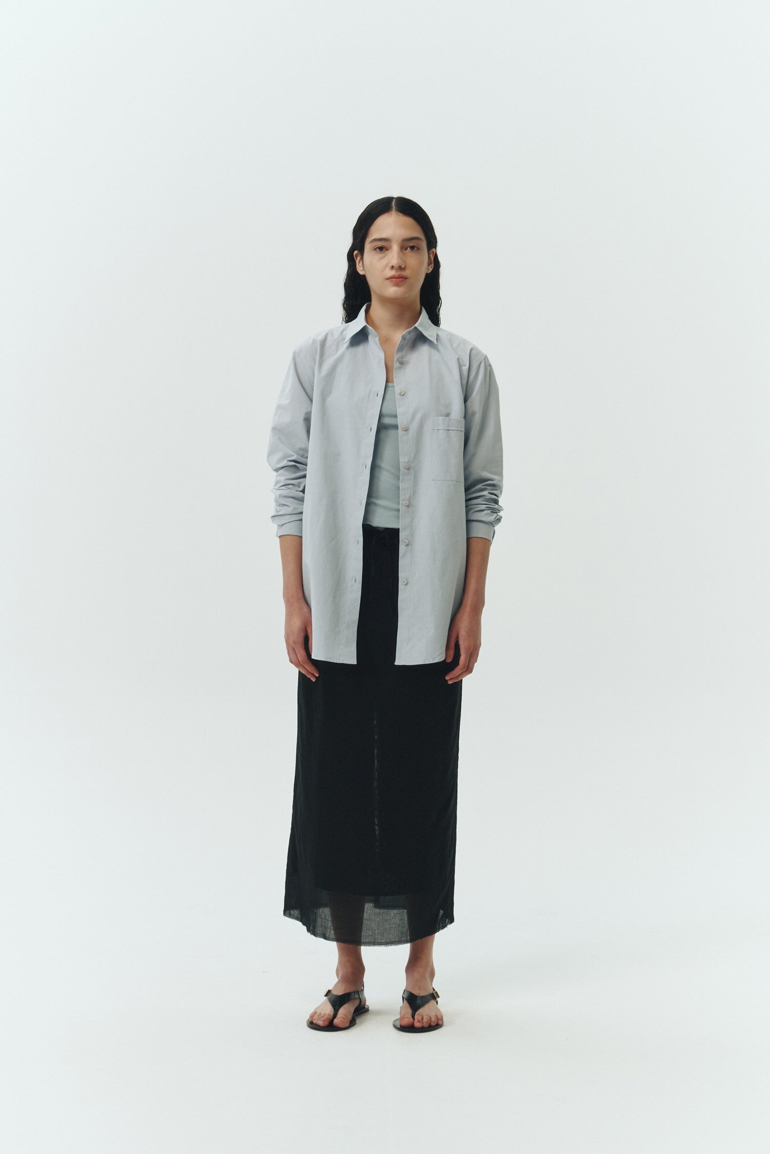 Amelia Skirt in black, a lightweight cotton midi skirt with inner drawstring waist, hidden side pockets, lined layers, raw-edge hem, and a center back slit for ease and movement