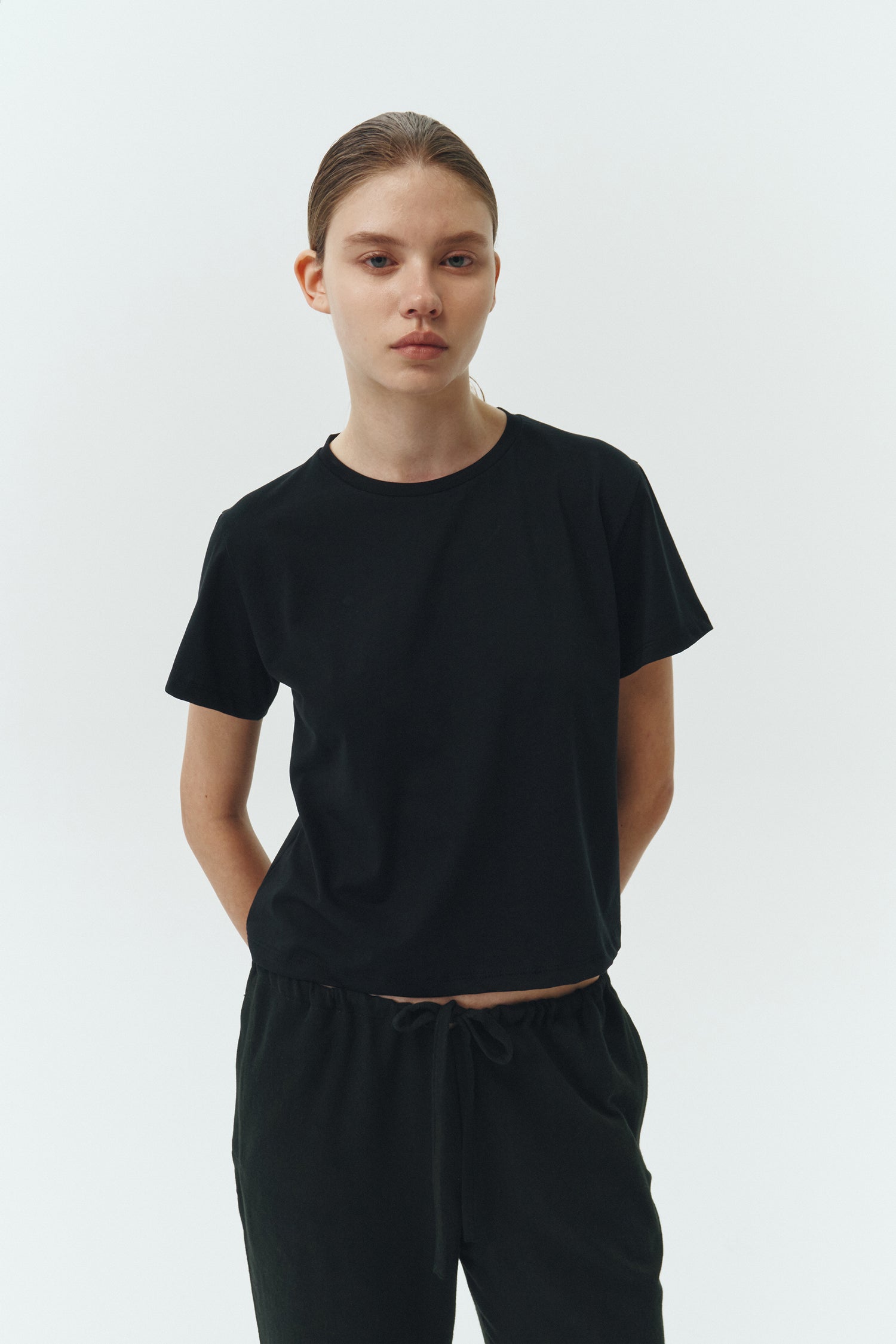 Chloe Pants in black, lightweight cotton pants with a drawstring waist, side pockets, and a flared bottom, relaxed fit for effortless everyday wear