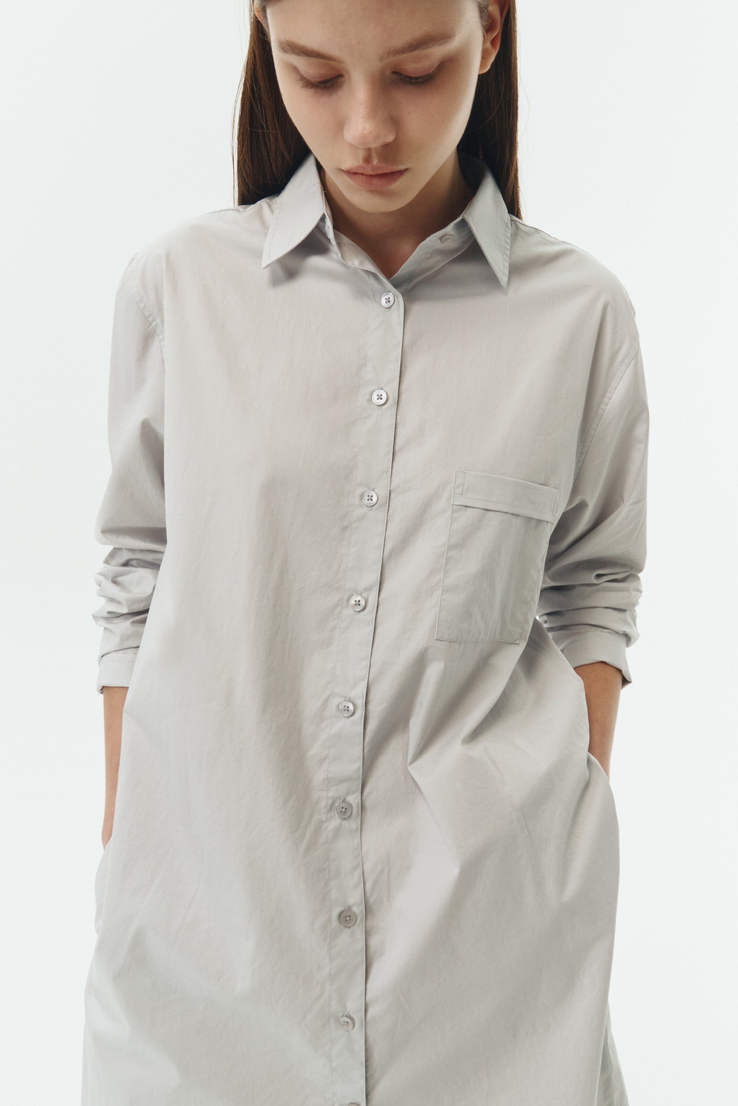 Cara Dress in cloud gray, long sleeve cotton shirt dress with front chest pocket, curved hem, hidden side pockets, and a relaxed silhouette.