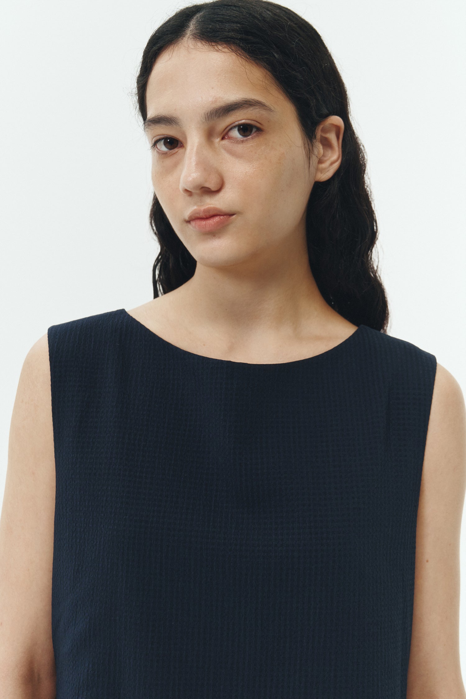 Pina Dress in navy, sleeveless cotton midi dress with shirring at waist and hem, hidden side pockets, and an open back with button closure.