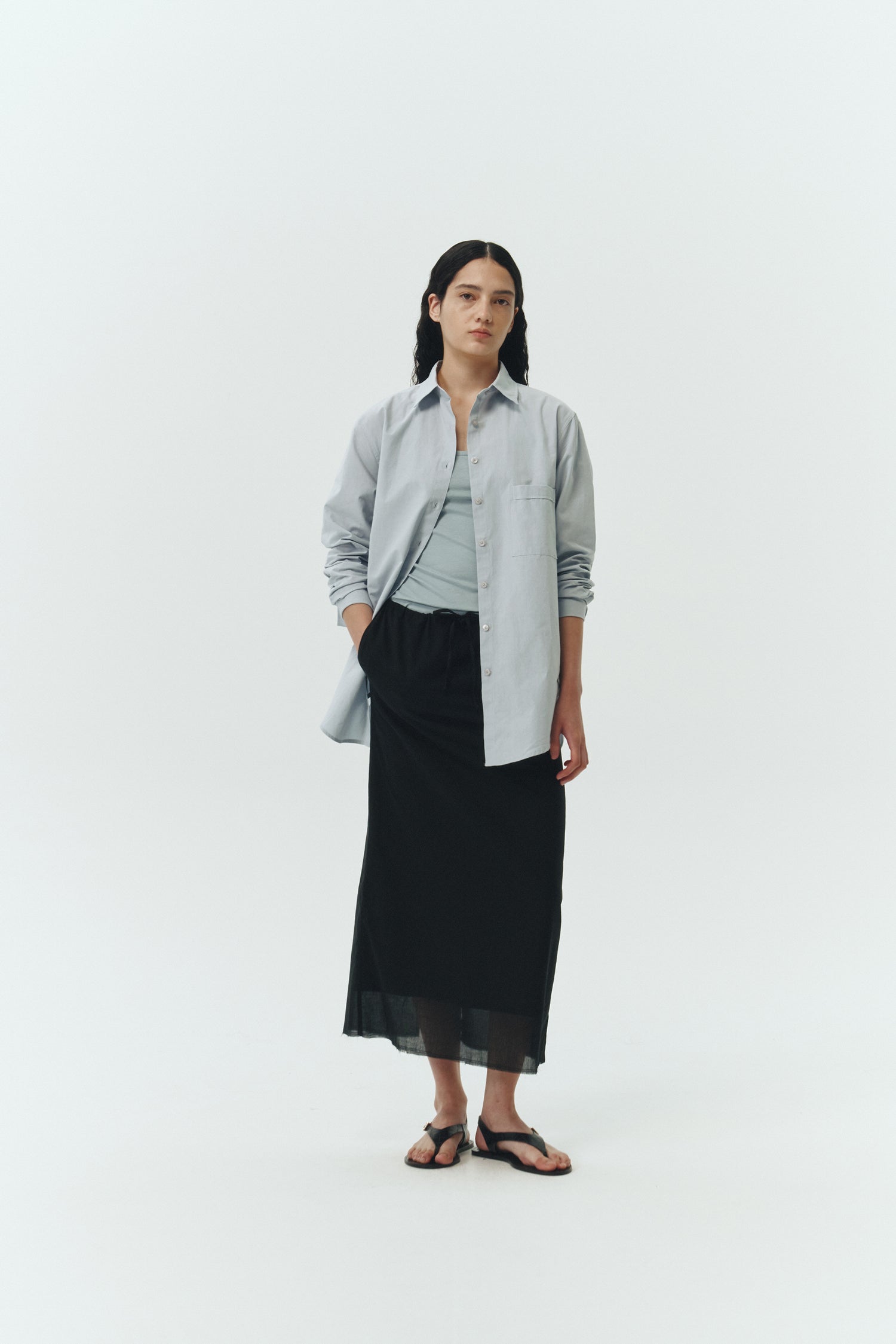Amelia Skirt in black, a lightweight cotton midi skirt with inner drawstring waist, hidden side pockets, lined layers, raw-edge hem, and a center back slit for ease and movement