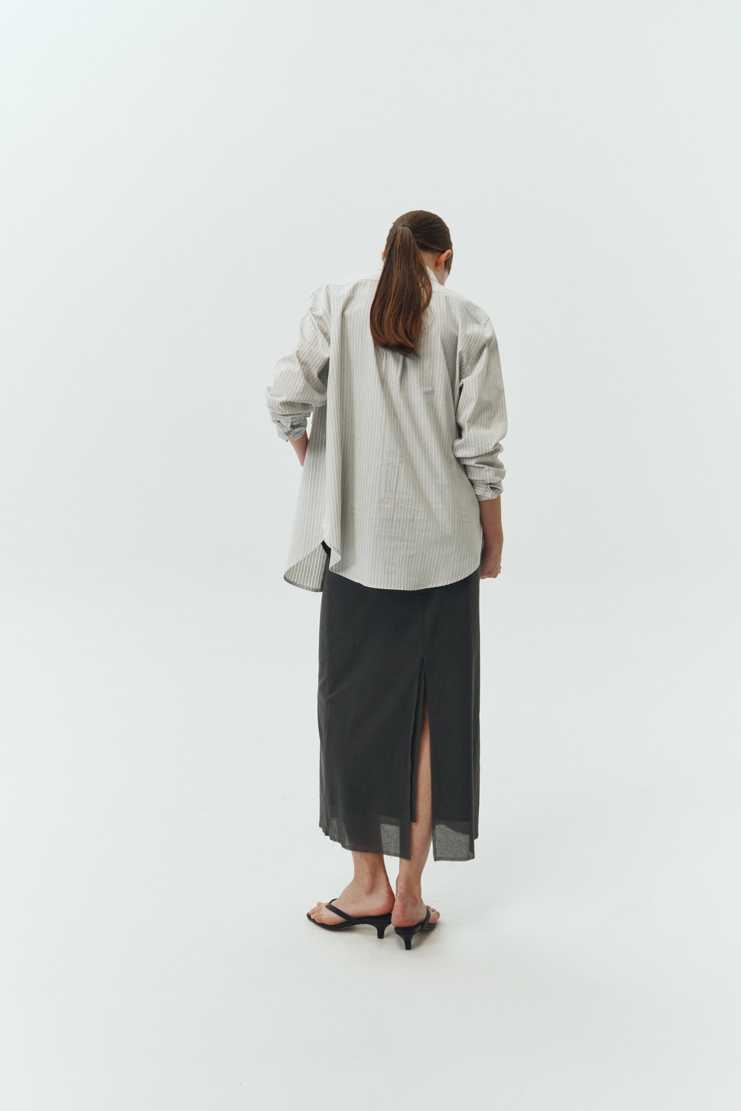 Amelia Skirt in charcoal, a lightweight cotton midi skirt with inner drawstring waist, hidden side pockets, lined layers, raw-edge hem, and a center back slit for ease and movement