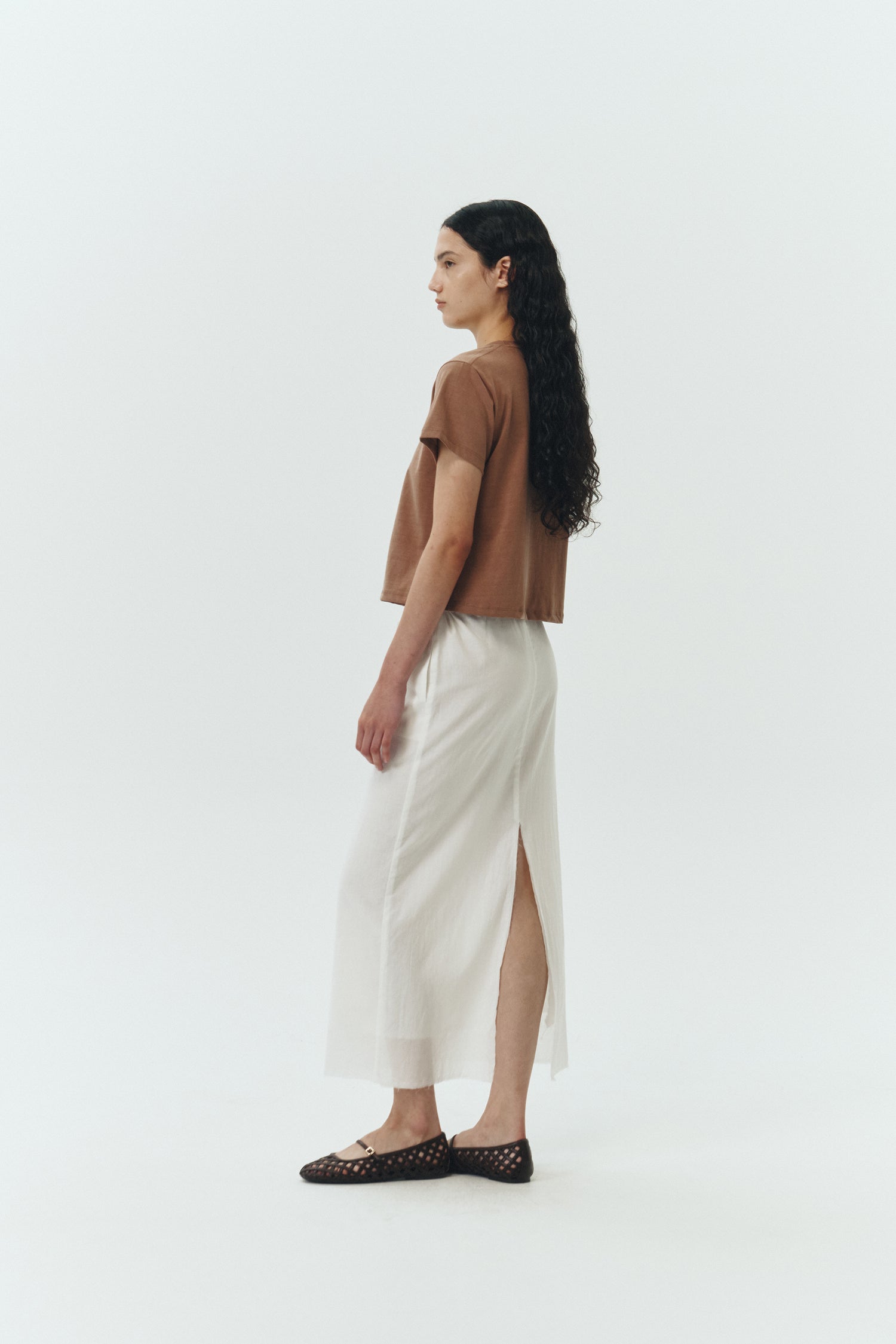 Amelia Skirt in white, a lightweight cotton midi skirt with inner drawstring waist, hidden side pockets, lined layers, raw-edge hem, and a center back slit for ease and movement