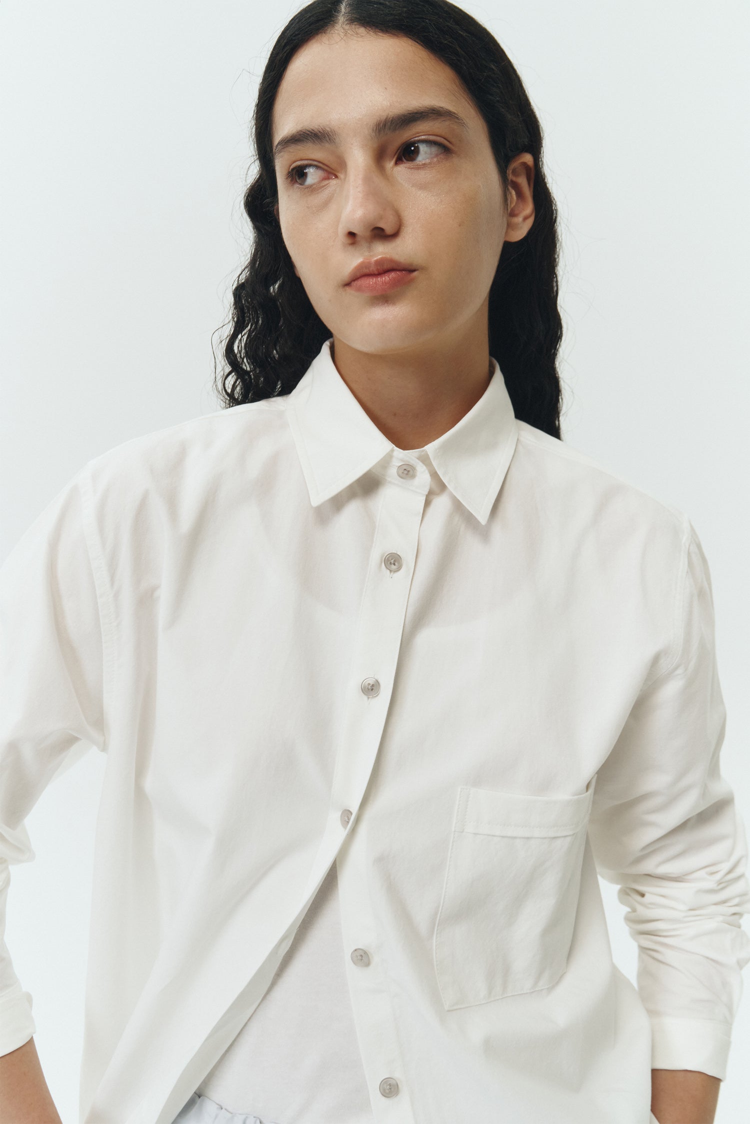 Isabella Shirt in white, a lightweight cotton-poly blend button-up with chest pocket, back pleat, and buttoned cuffs, designed in a regular fit with a hip-length silhouette