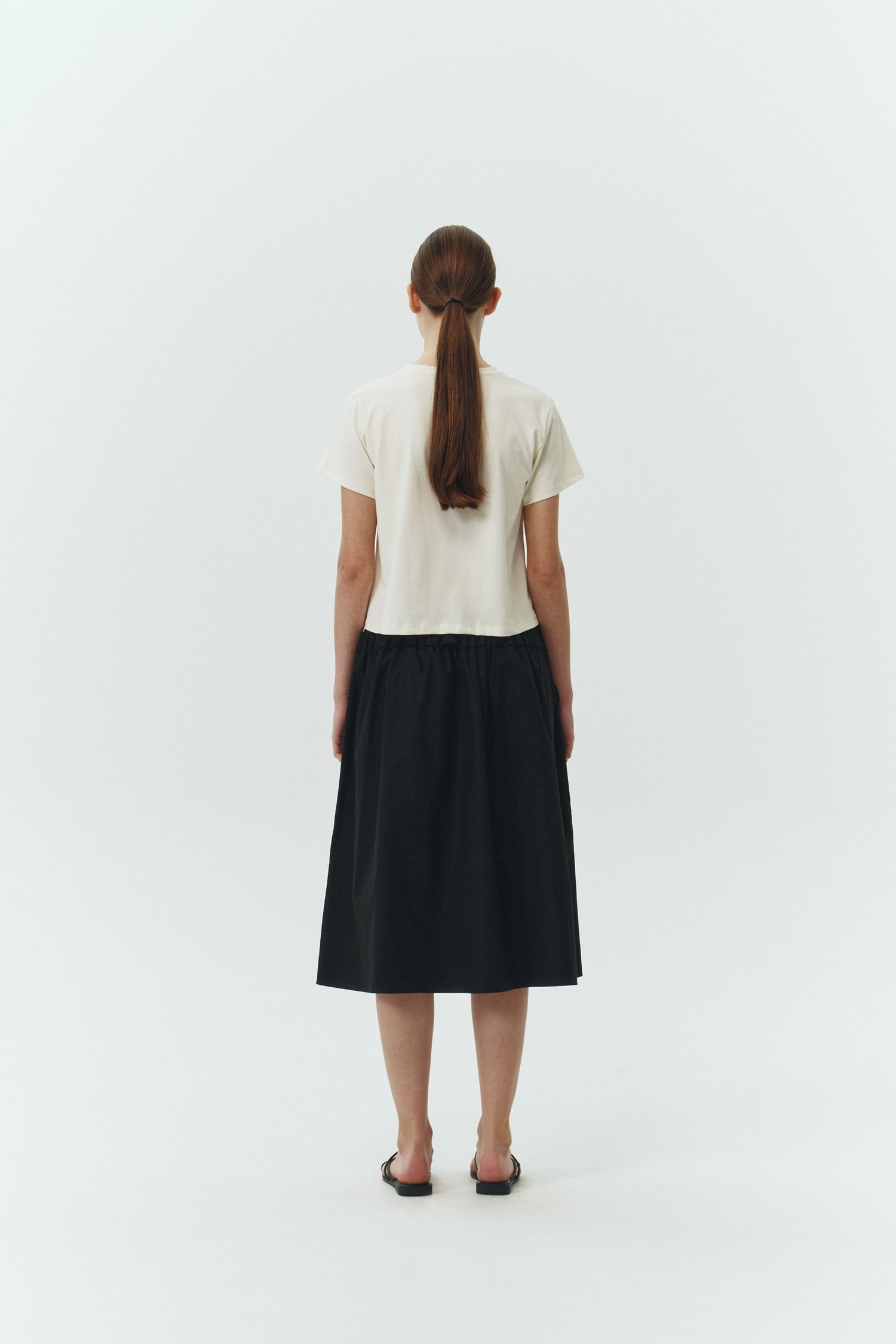 Maryam Skirt in black, a midi cotton skirt with shirred waistband, drawstring detail, side pockets, and a softly flared silhouette