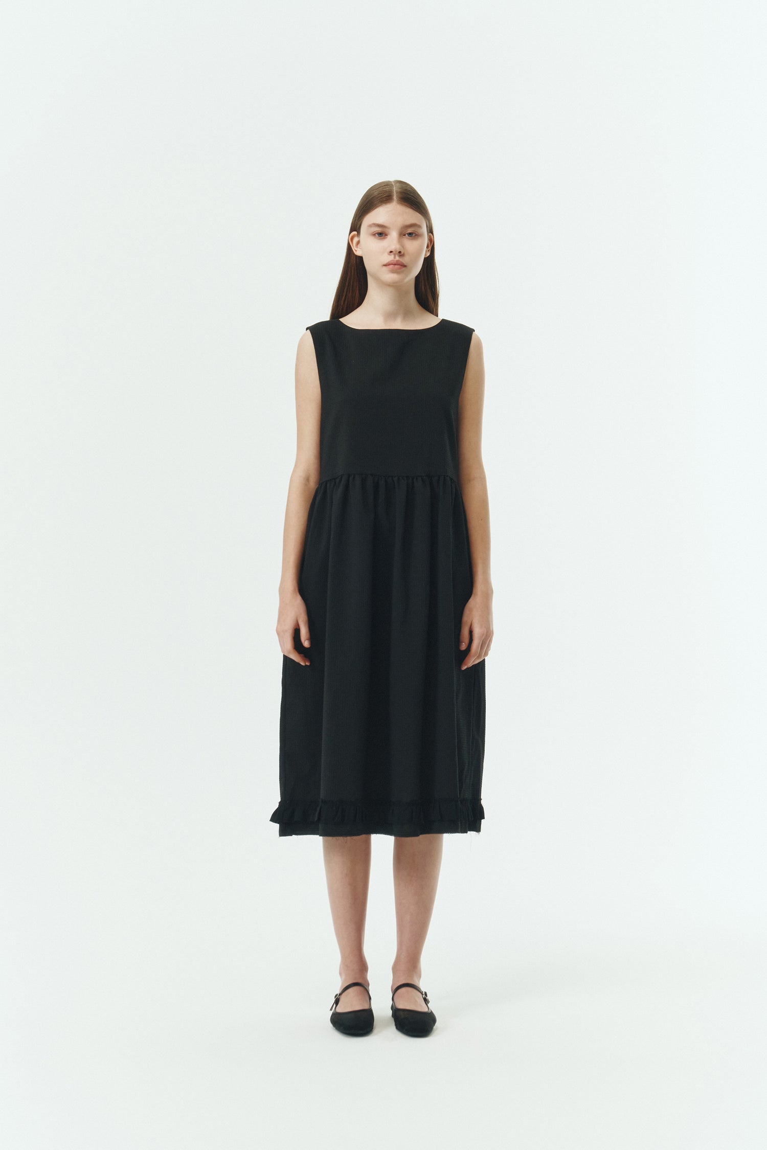Pina Dress in black, sleeveless cotton midi dress with shirring at waist and hem, hidden side pockets, and an open back with button closure.