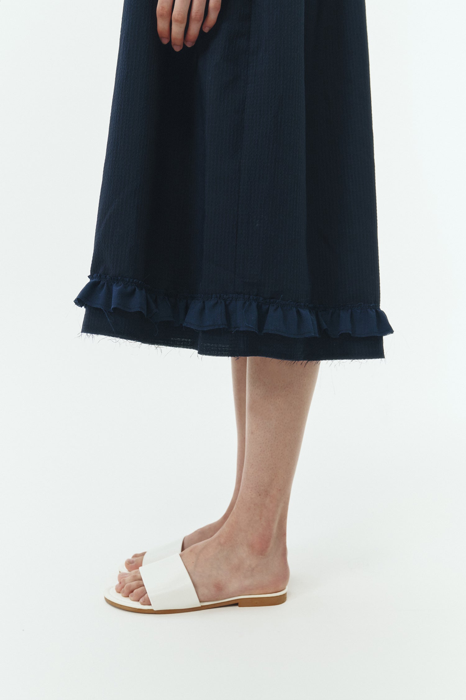 Pina Dress in navy, sleeveless cotton midi dress with shirring at waist and hem, hidden side pockets, and an open back with button closure.