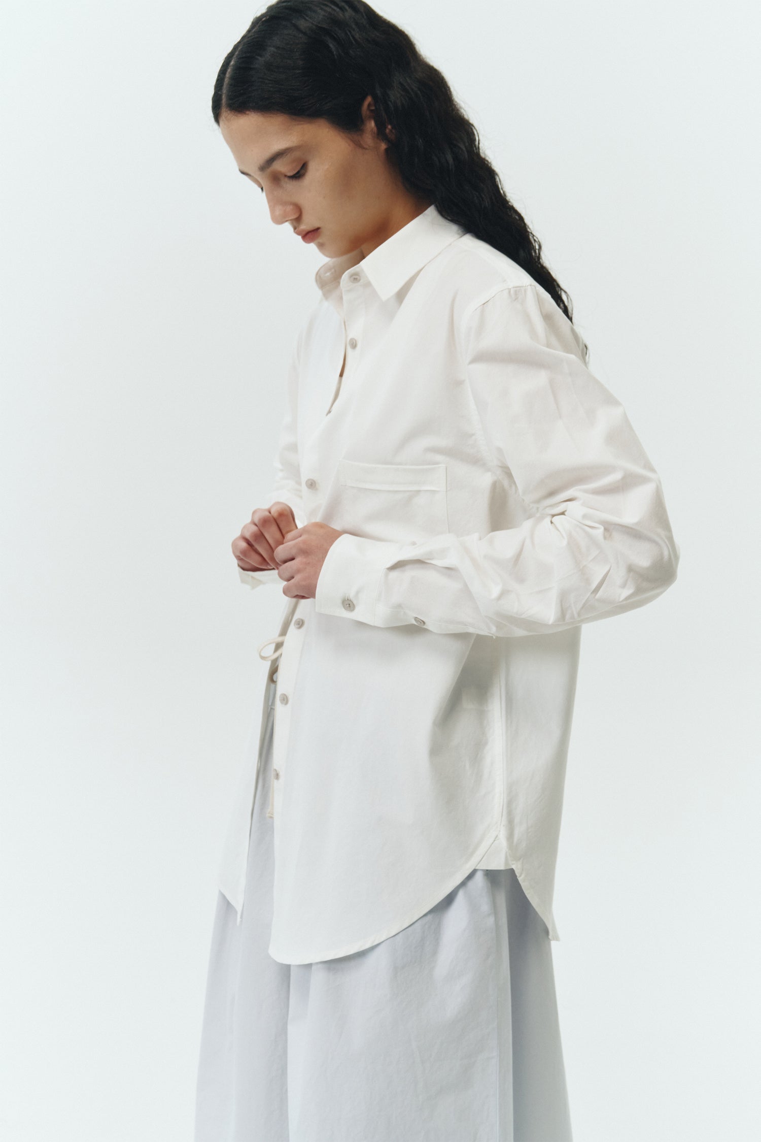 Isabella Shirt in white, a lightweight cotton-poly blend button-up with chest pocket, back pleat, and buttoned cuffs, designed in a regular fit with a hip-length silhouette