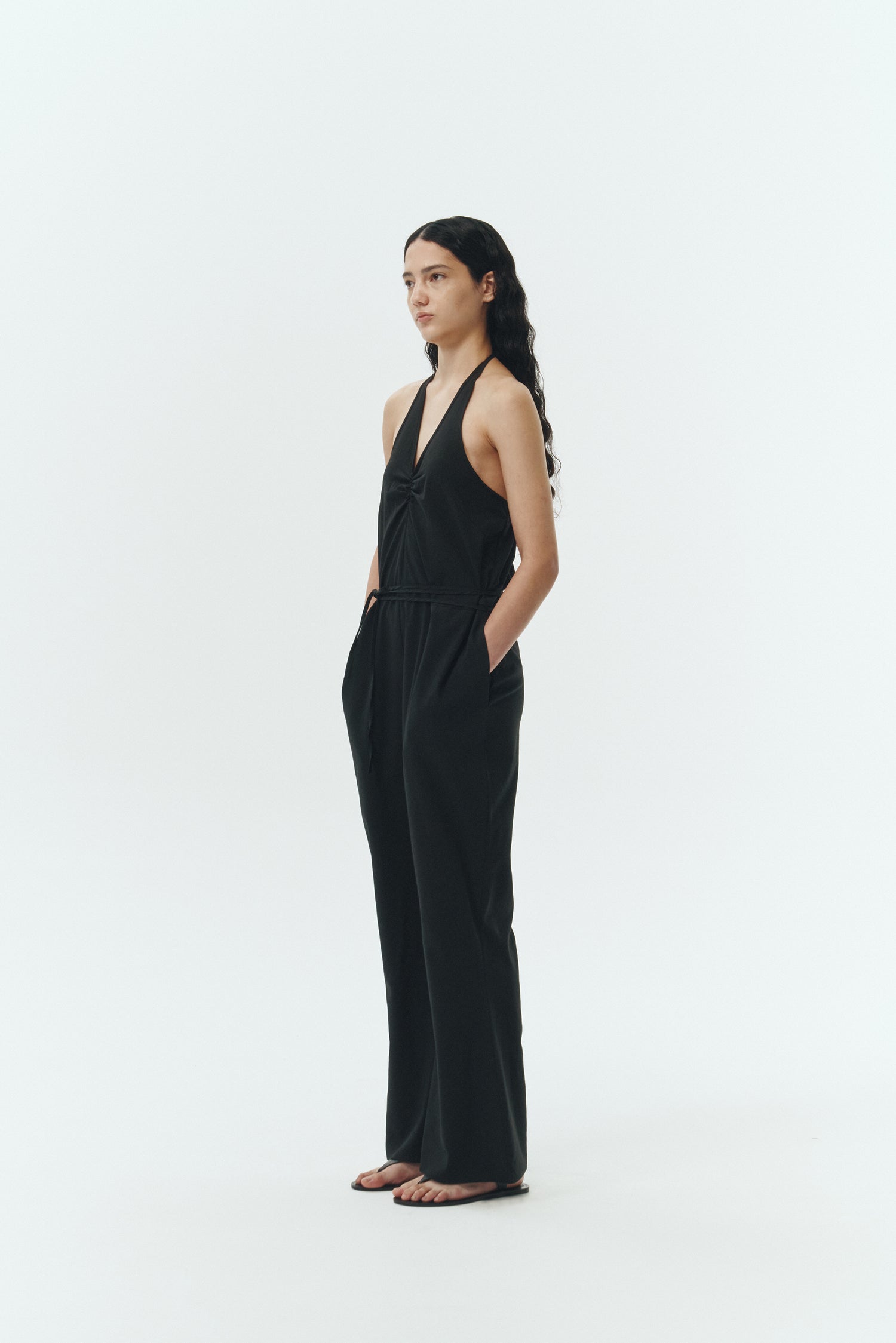 Daisy Jumpsuit in black, sleeveless linen blend jumpsuit with adjustable halterneck, open back, straight-leg silhouette, and relaxed fit.