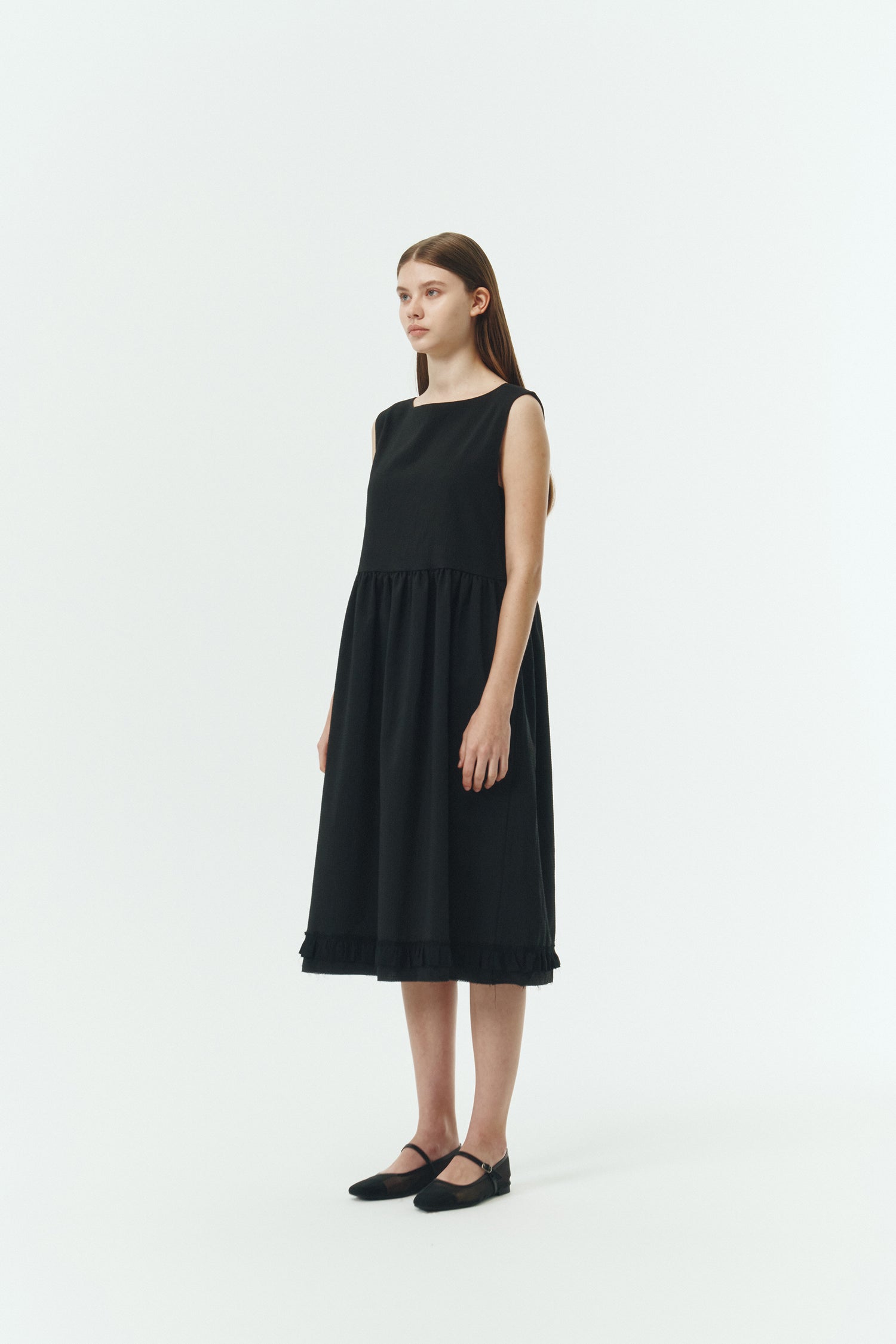 Pina Dress in black, sleeveless cotton midi dress with shirring at waist and hem, hidden side pockets, and an open back with button closure.
