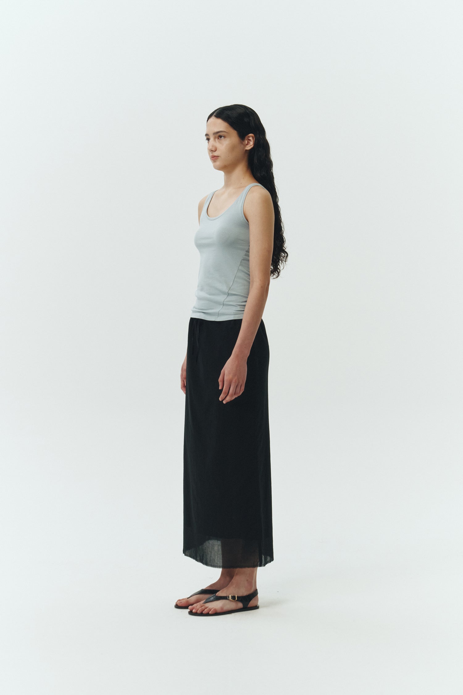 Amelia Skirt in black, a lightweight cotton midi skirt with inner drawstring waist, hidden side pockets, lined layers, raw-edge hem, and a center back slit for ease and movement