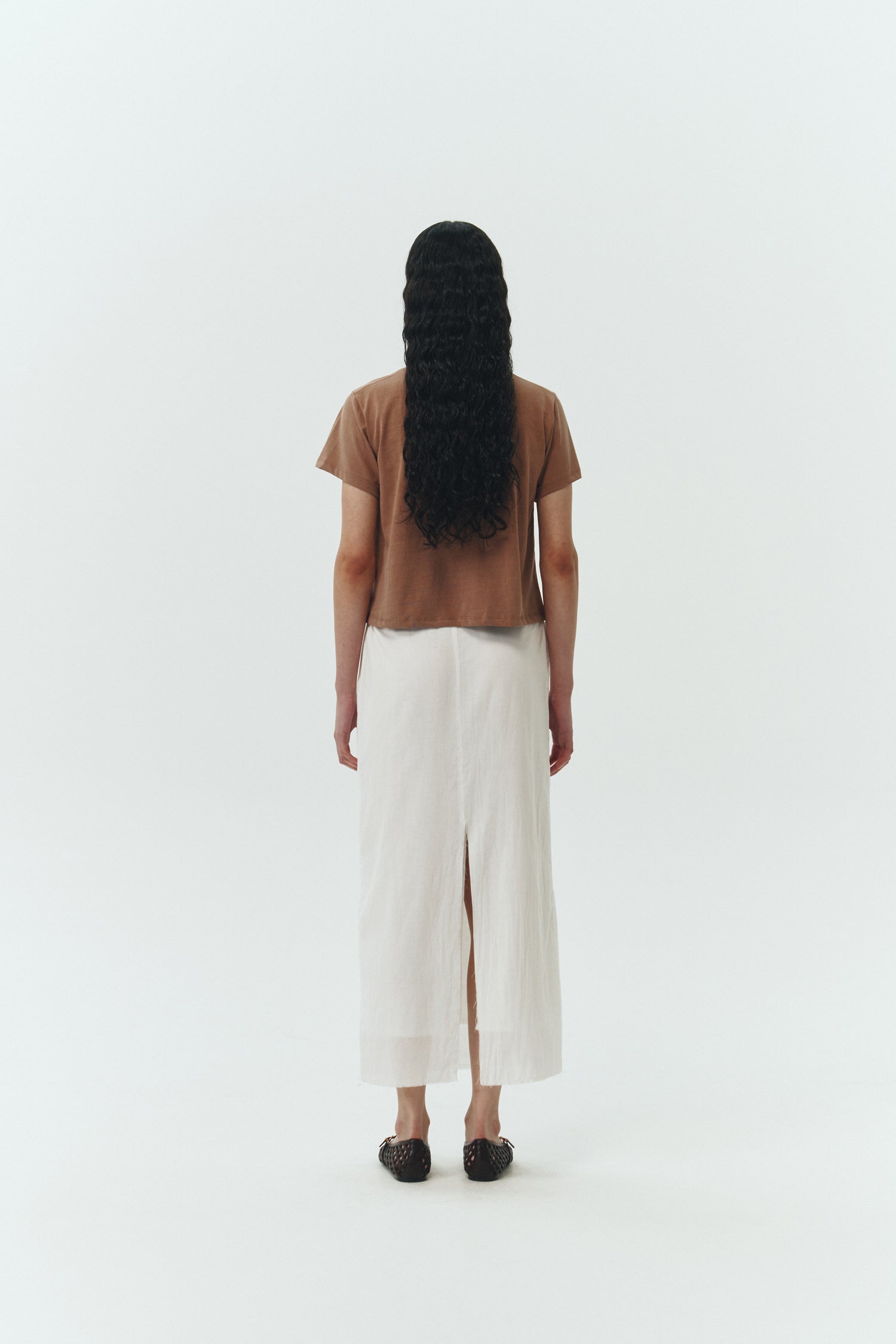 Amelia Skirt in white, a lightweight cotton midi skirt with inner drawstring waist, hidden side pockets, lined layers, raw-edge hem, and a center back slit for ease and movement