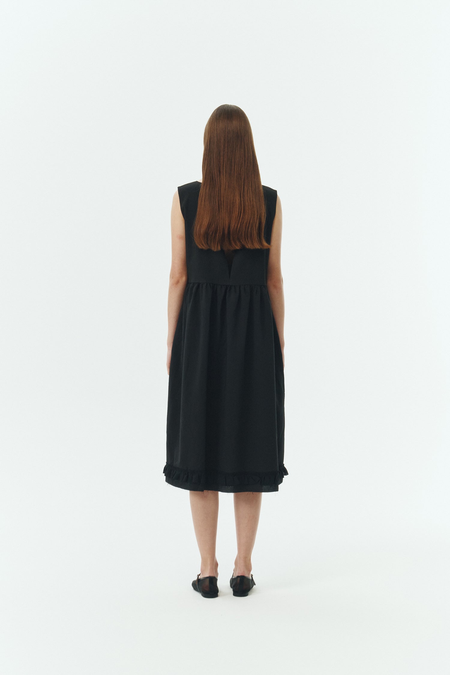 Pina Dress in black, sleeveless cotton midi dress with shirring at waist and hem, hidden side pockets, and an open back with button closure.
