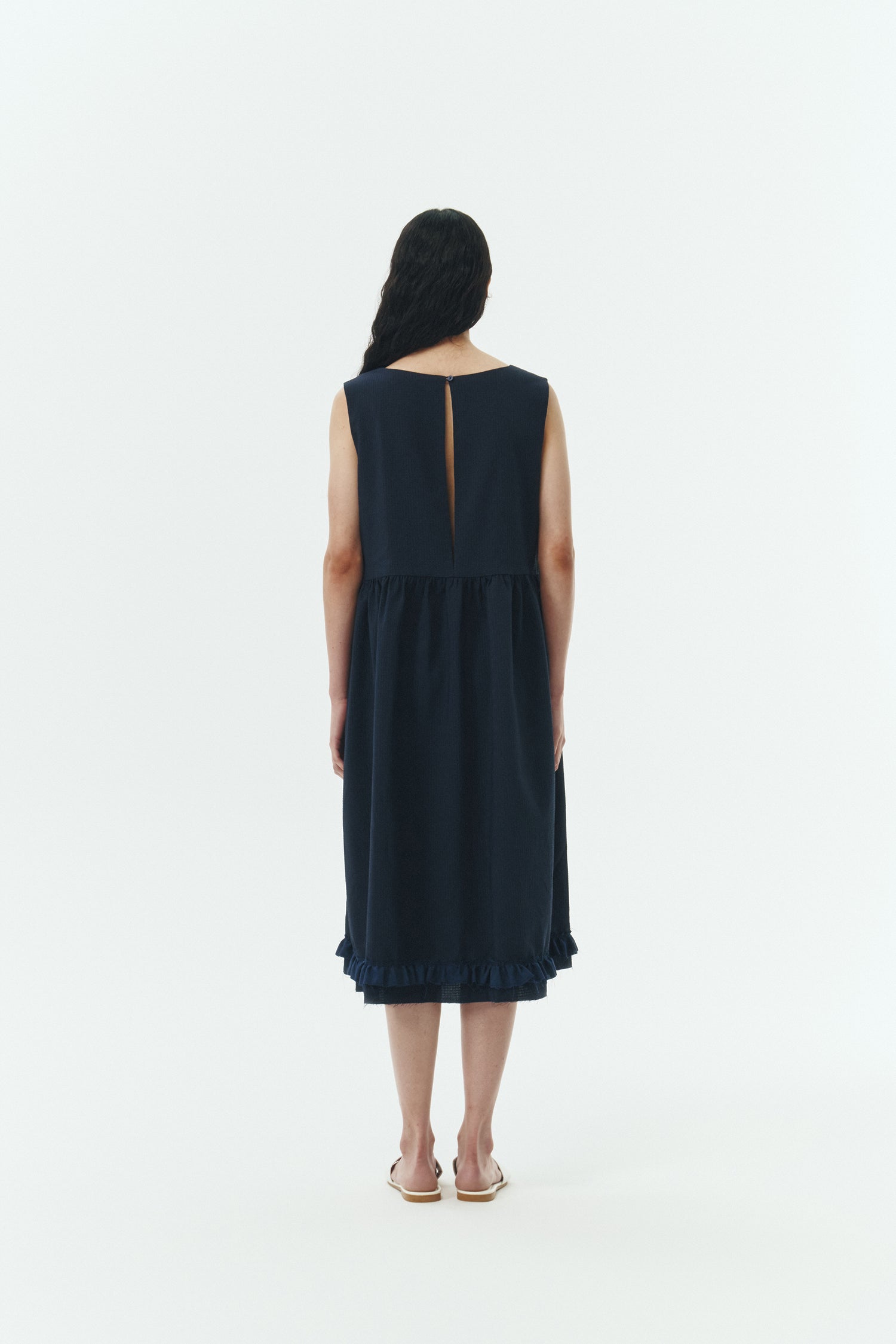 Pina Dress in navy, sleeveless cotton midi dress with shirring at waist and hem, hidden side pockets, and an open back with button closure.