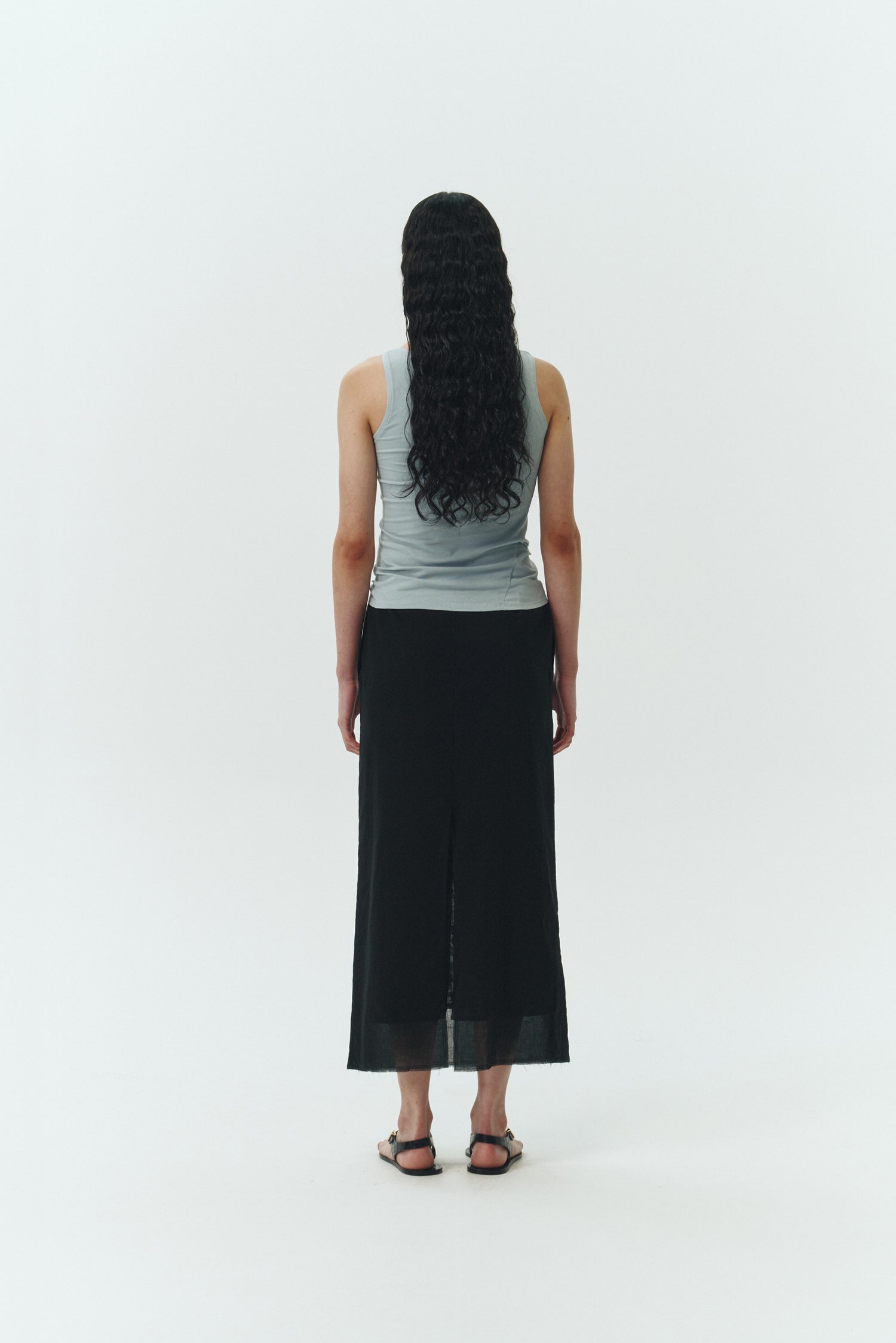 Amelia Skirt in black, a lightweight cotton midi skirt with inner drawstring waist, hidden side pockets, lined layers, raw-edge hem, and a center back slit for ease and movement