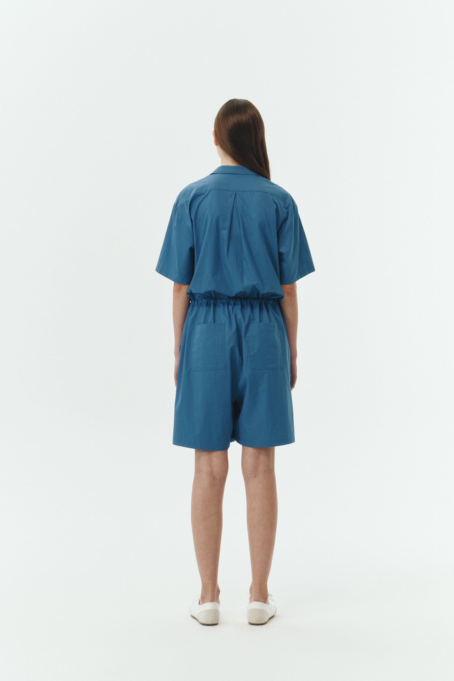 Emma Jumpsuit in blue green, short-sleeve cotton jumpsuit with camp collar, front buttons, drawstring waist, and multiple pockets.