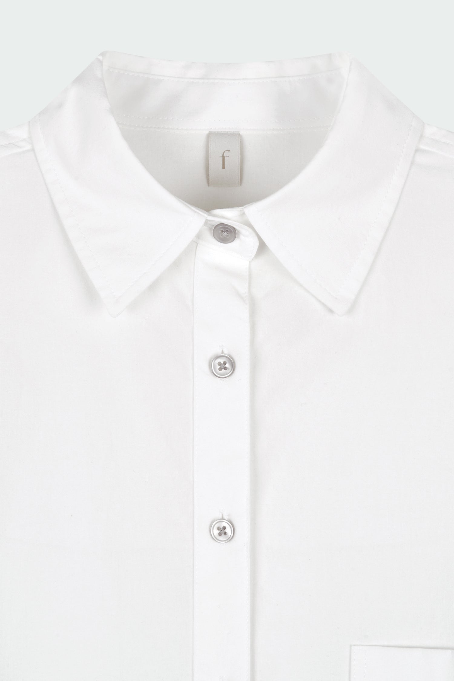 Isabella Shirt in white, a lightweight cotton-poly blend button-up with chest pocket, back pleat, and buttoned cuffs, designed in a regular fit with a hip-length silhouette