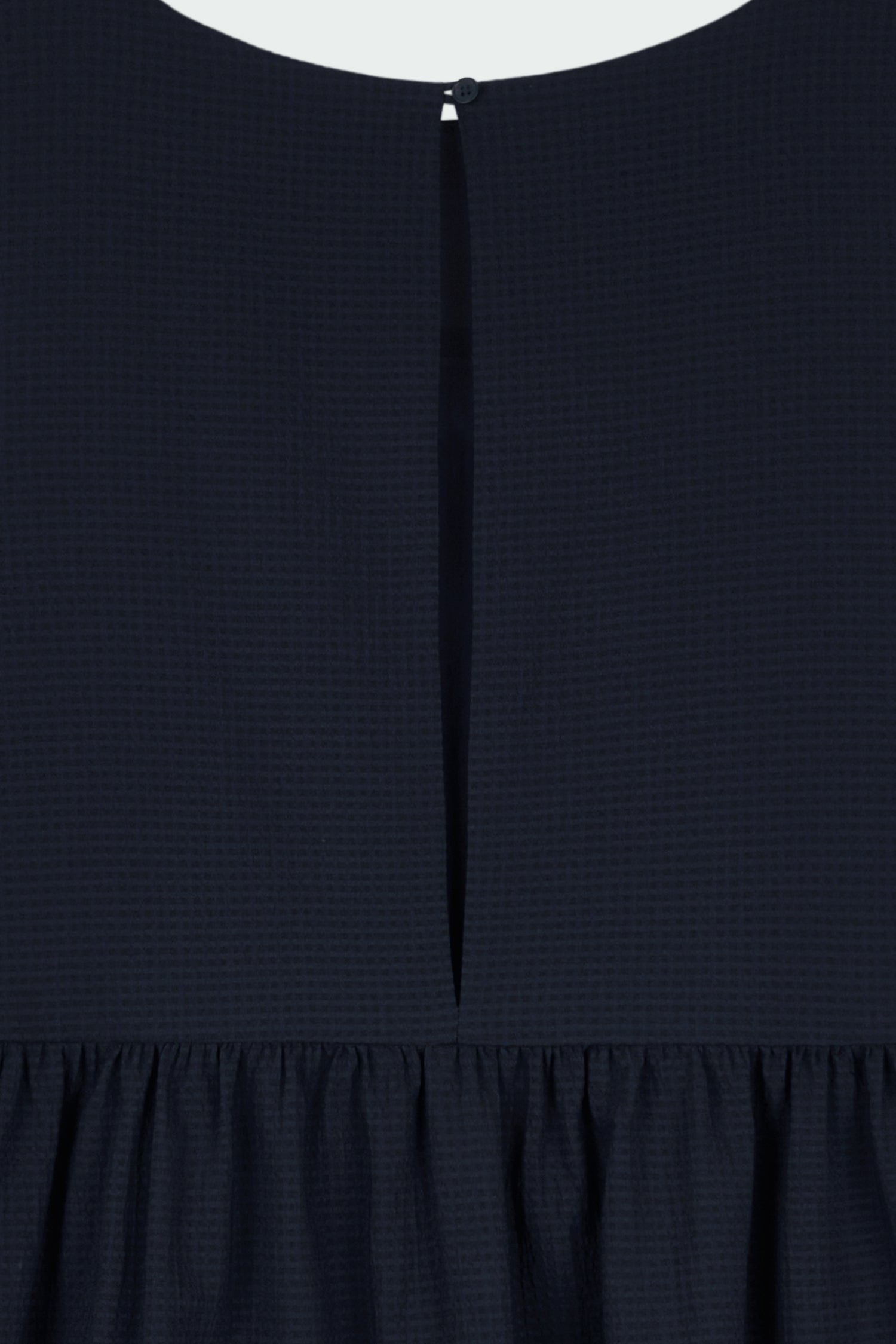 Pina Dress in navy, sleeveless cotton midi dress with shirring at waist and hem, hidden side pockets, and an open back with button closure.