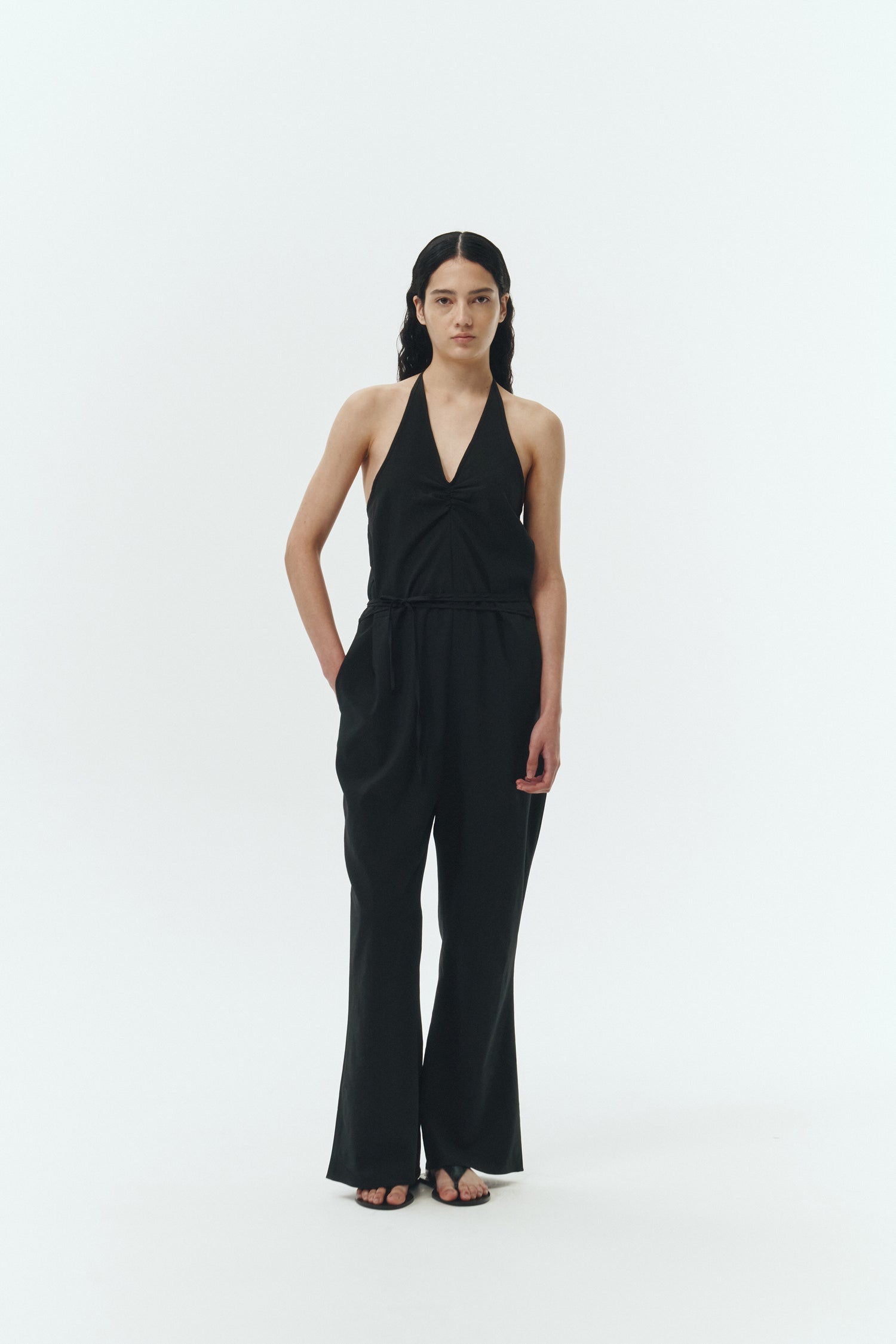 Daisy Jumpsuit in black, sleeveless linen blend jumpsuit with adjustable halterneck, open back, straight-leg silhouette, and relaxed fit.