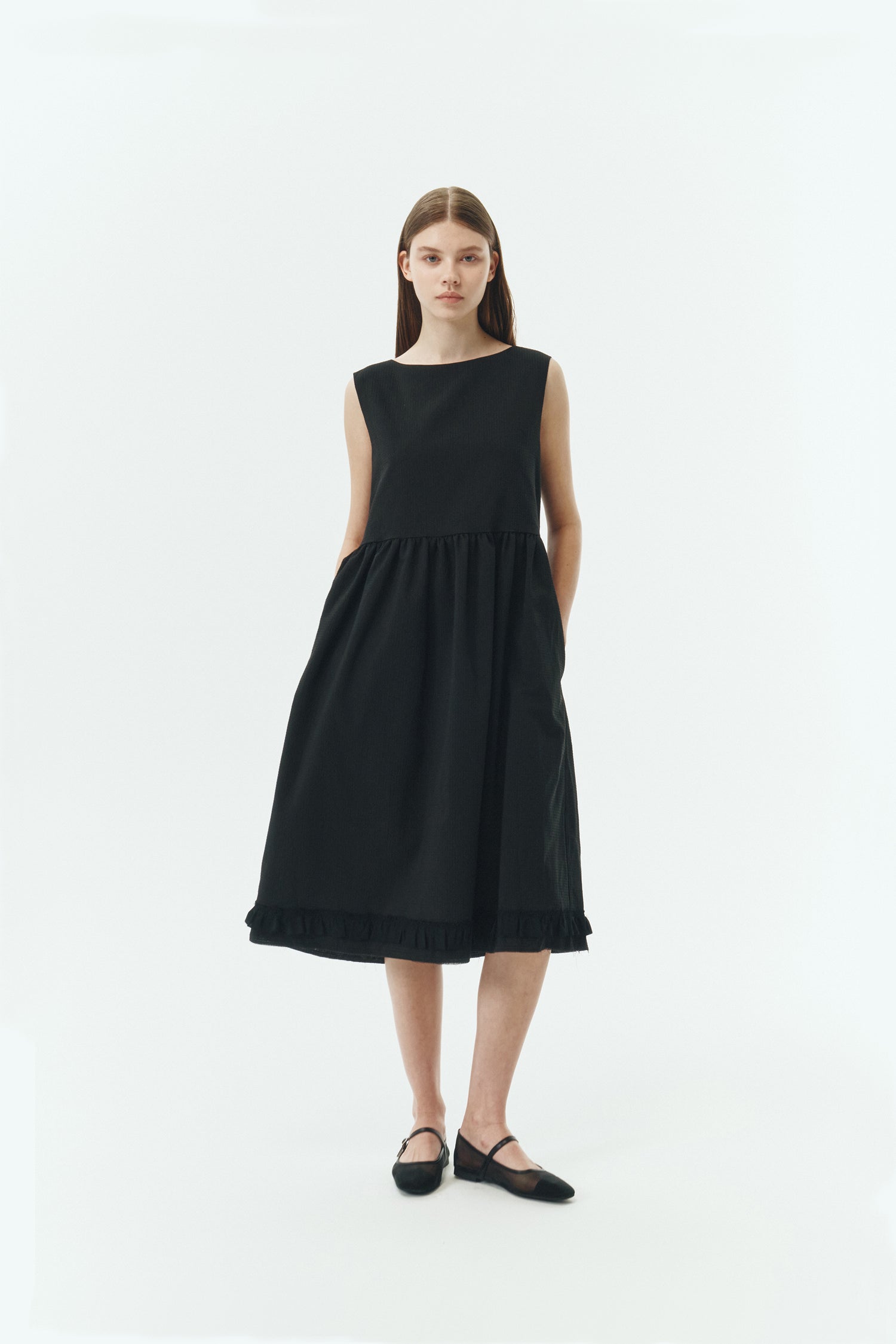 Pina Dress in black, sleeveless cotton midi dress with shirring at waist and hem, hidden side pockets, and an open back with button closure.