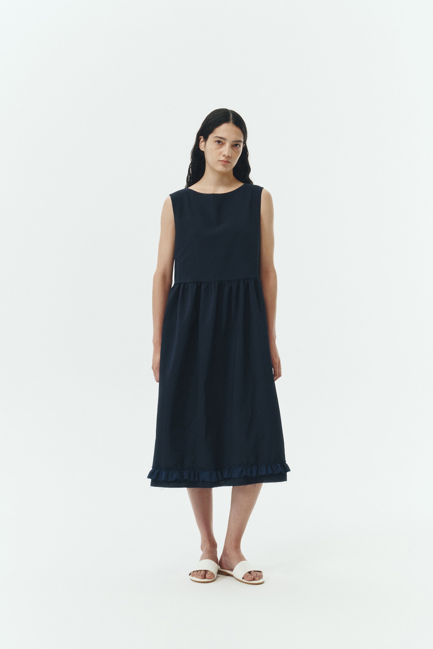 Pina Dress in navy, sleeveless cotton midi dress with shirring at waist and hem, hidden side pockets, and an open back with button closure.
