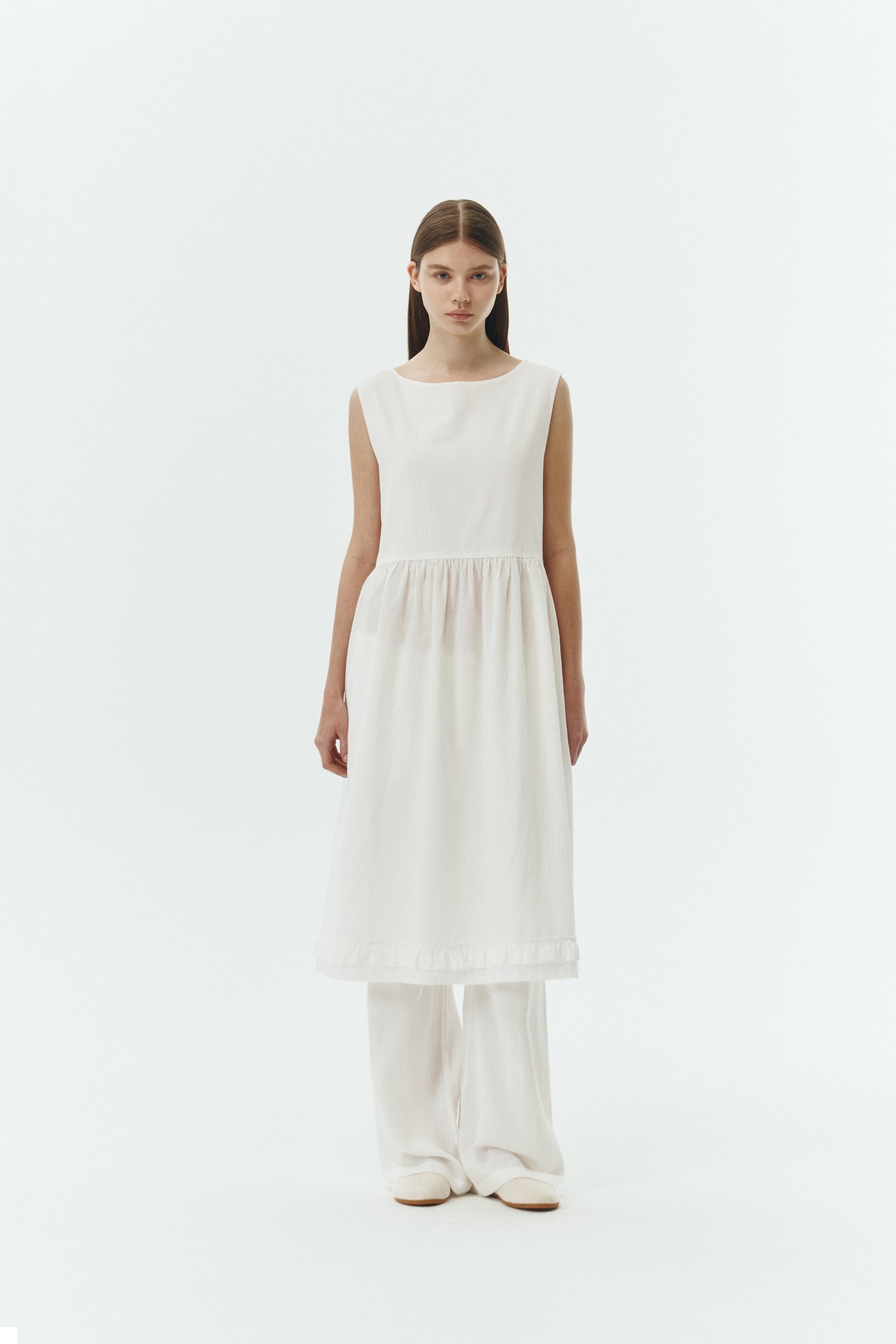 Pina Dress in white a sleeveless midi dress with an open back and button closure, featuring shirring details at the waist and hem, plus hidden side pockets for summer comfort