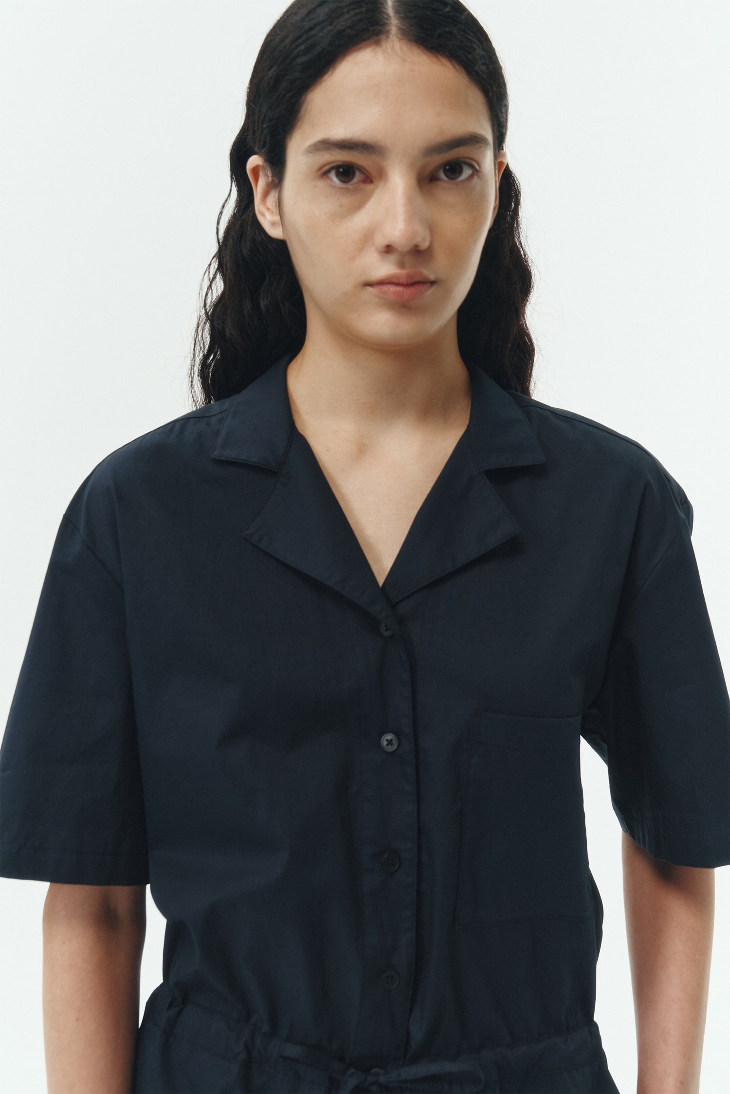 Emma Jumpsuit in navy, short-sleeve cotton jumpsuit with camp collar, front buttons, drawstring waist, and multiple pockets.