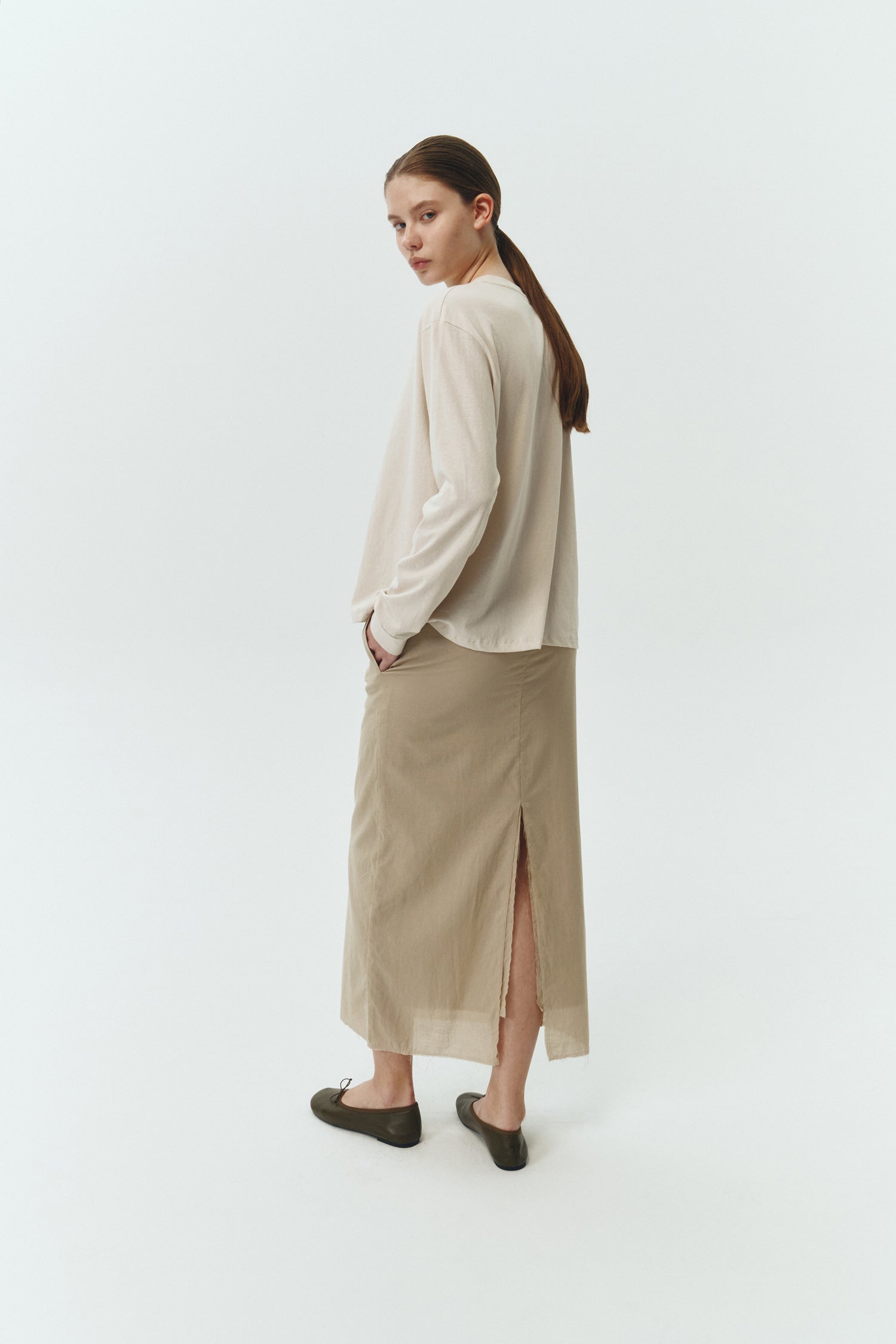 Amelia Skirt in sand, a lightweight cotton midi skirt with inner drawstring waist, hidden side pockets, lined layers, raw-edge hem, and a center back slit for ease and movement