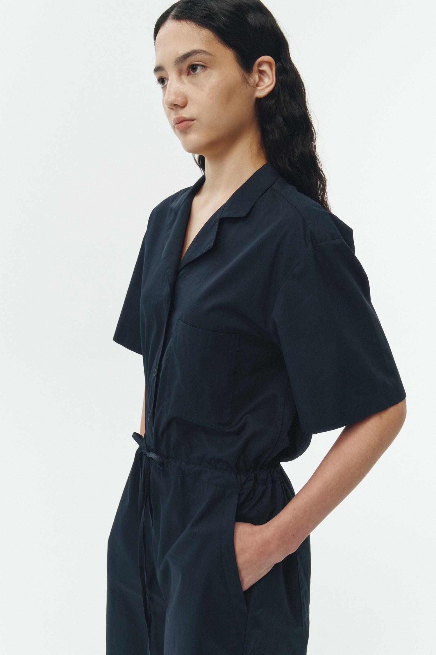 Emma Jumpsuit in navy, short-sleeve cotton jumpsuit with camp collar, front buttons, drawstring waist, and multiple pockets.