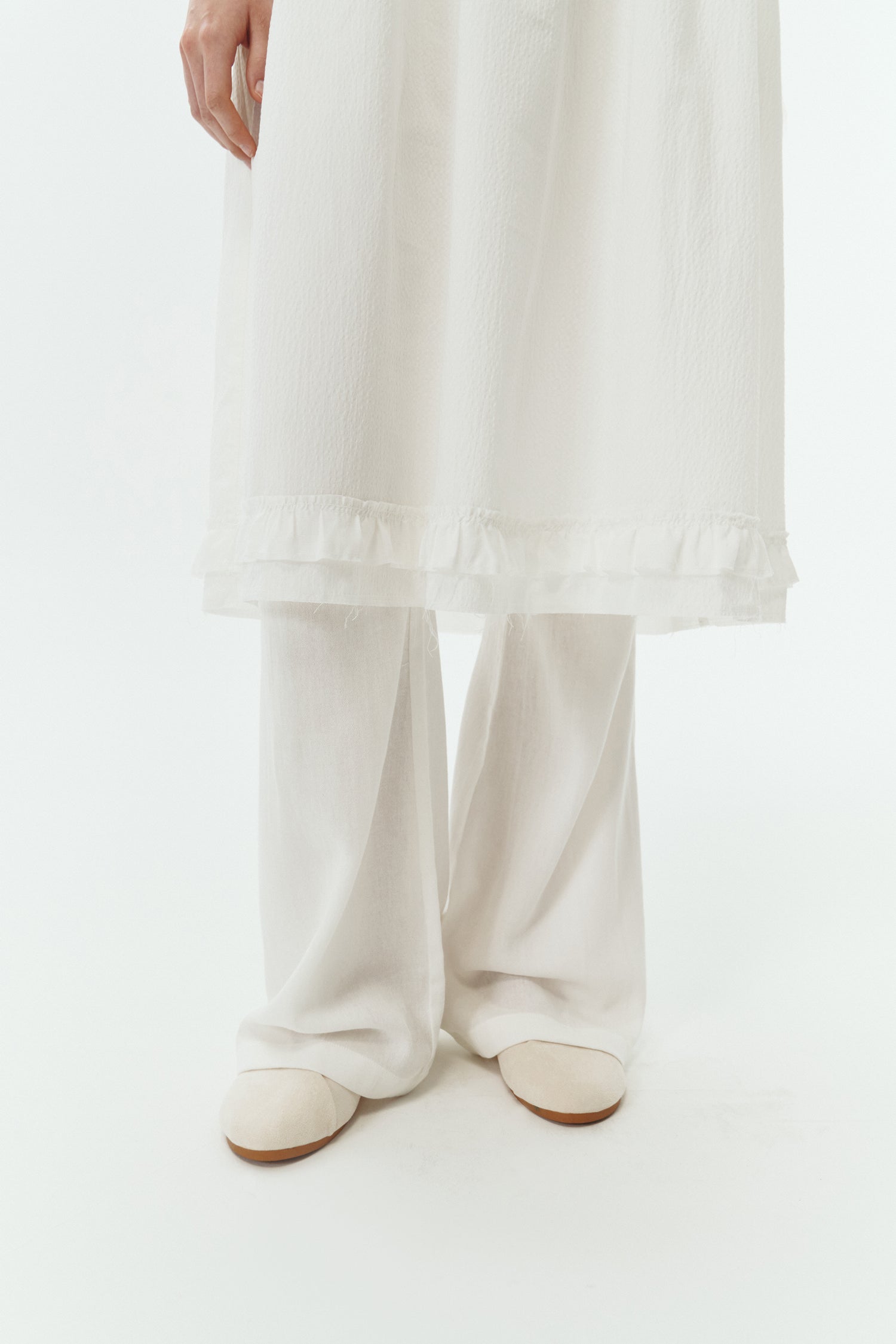 Pina Dress in white a sleeveless midi dress with an open back and button closure, featuring shirring details at the waist and hem, plus hidden side pockets for summer comfort