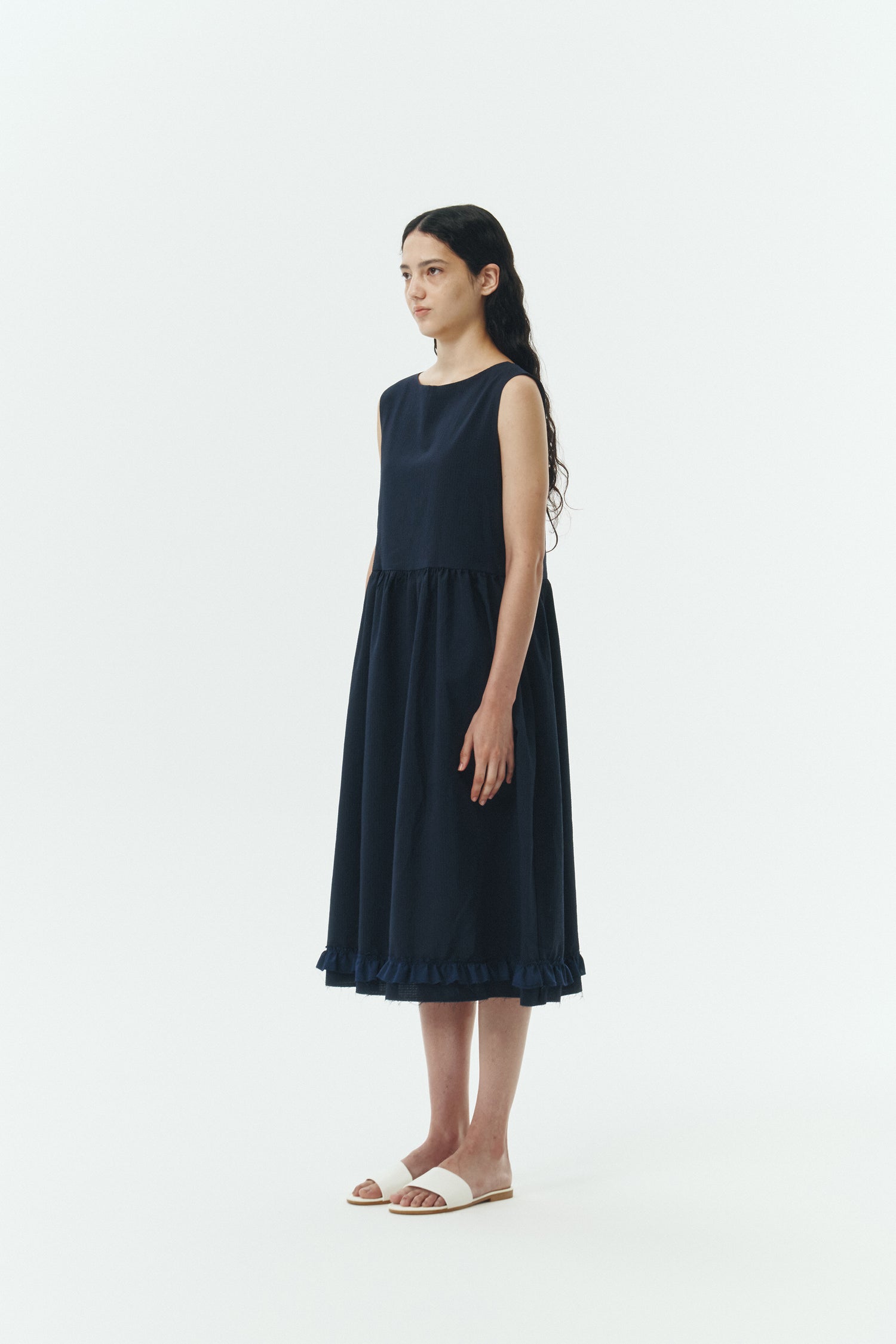Pina Dress in navy, sleeveless cotton midi dress with shirring at waist and hem, hidden side pockets, and an open back with button closure.