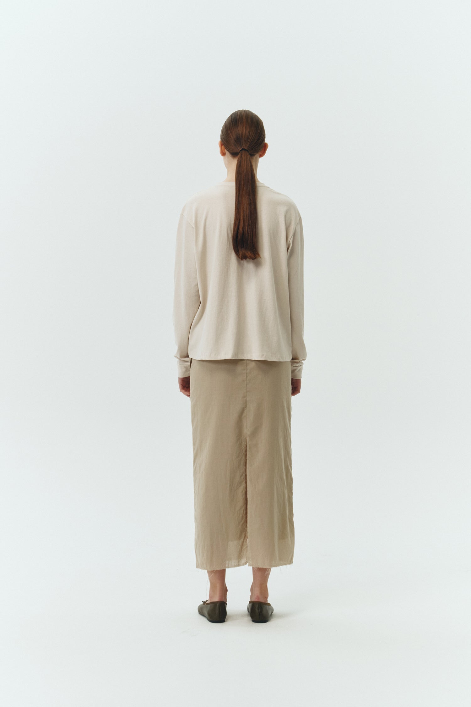 Amelia Skirt in sand, a lightweight cotton midi skirt with inner drawstring waist, hidden side pockets, lined layers, raw-edge hem, and a center back slit for ease and movement