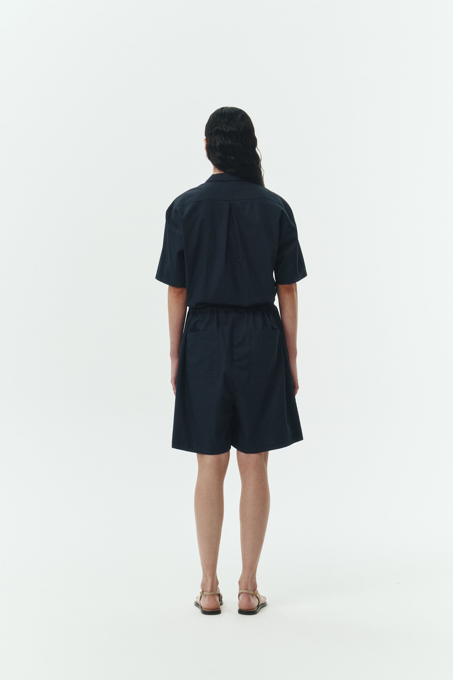 Emma Jumpsuit in navy, short-sleeve cotton jumpsuit with camp collar, front buttons, drawstring waist, and multiple pockets.