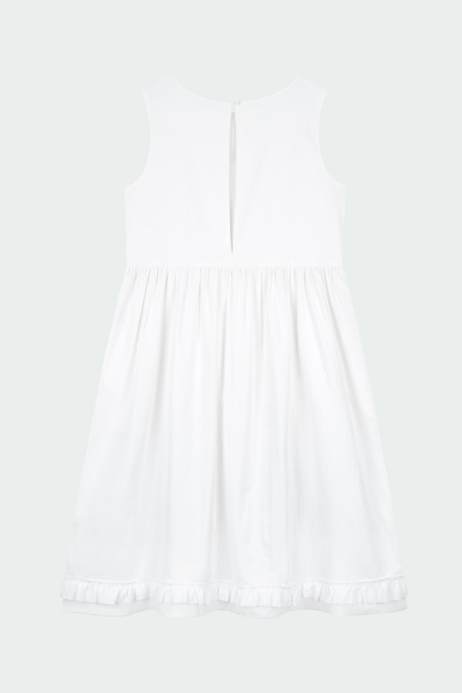Pina Dress in white a sleeveless midi dress with an open back and button closure, featuring shirring details at the waist and hem, plus hidden side pockets for summer comfort