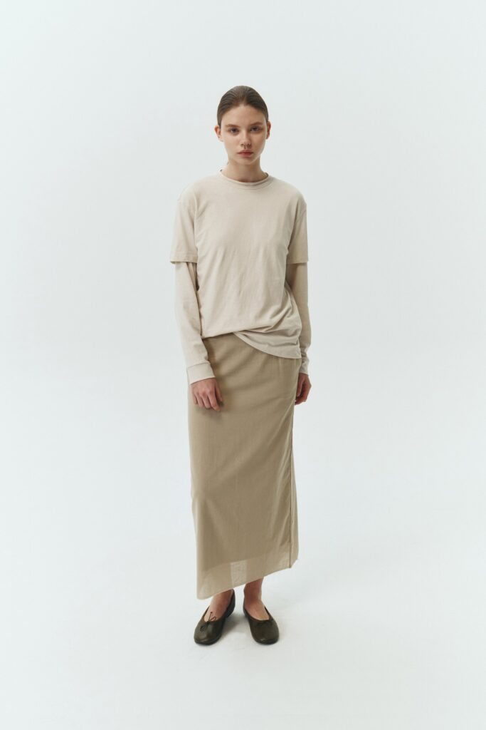 Amelia Skirt in sand, a lightweight cotton midi skirt with inner drawstring waist, hidden side pockets, lined layers, raw-edge hem, and a center back slit for ease and movement