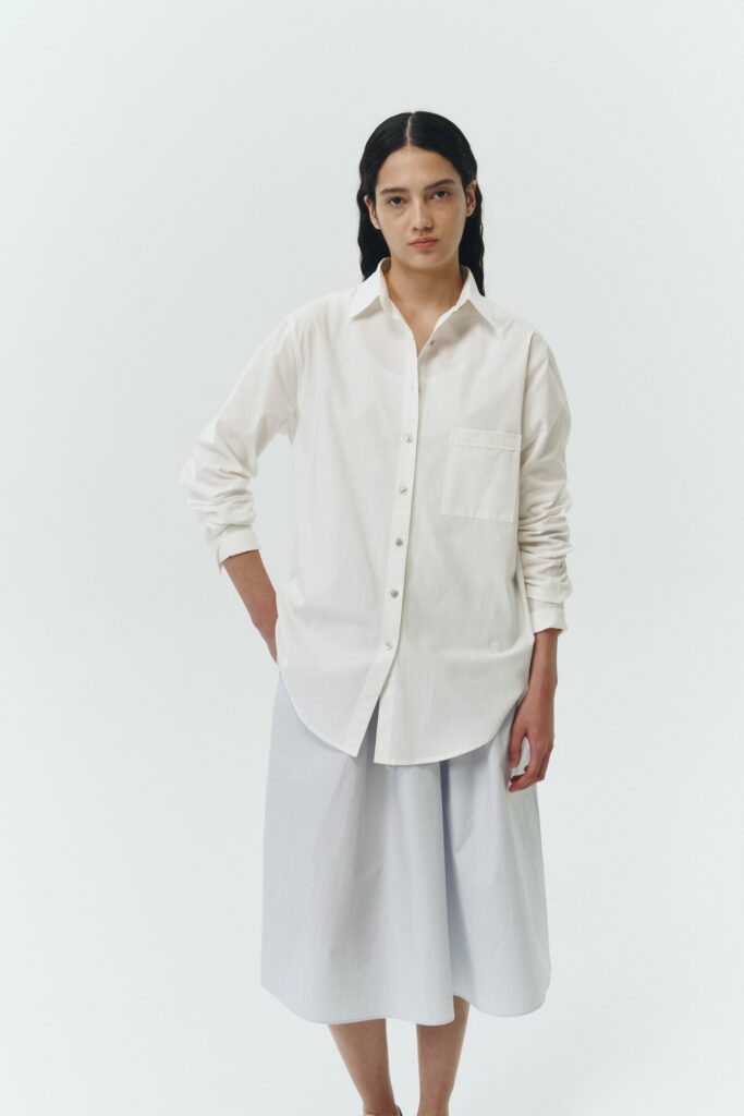 Isabella Shirt in white, a lightweight cotton-poly blend button-up with chest pocket, back pleat, and buttoned cuffs, designed in a regular fit with a hip-length silhouette
