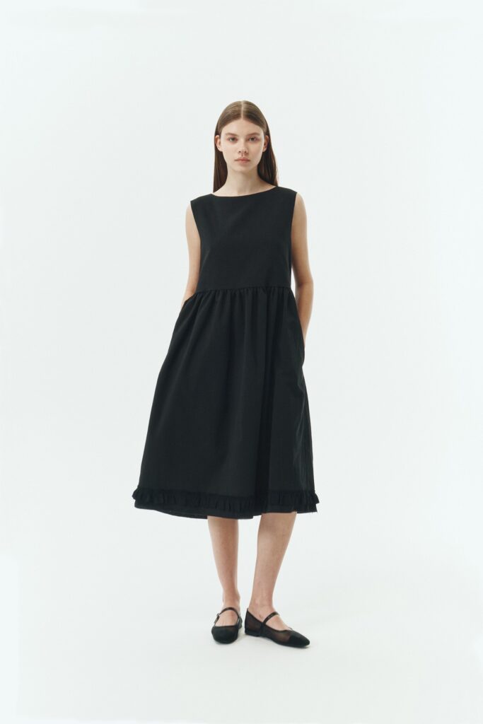 Pina Dress in black, sleeveless cotton midi dress with shirring at waist and hem, hidden side pockets, and an open back with button closure.